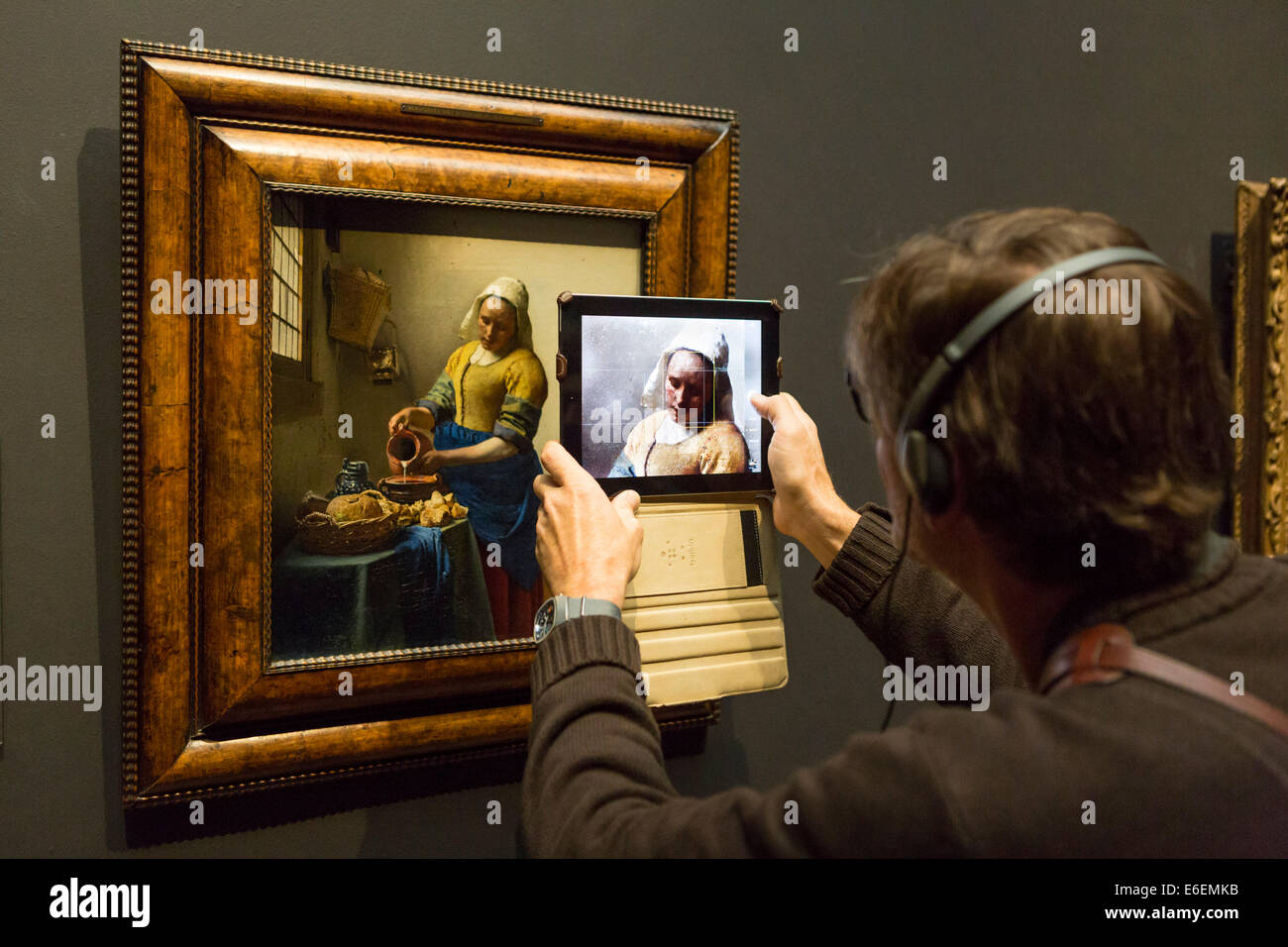 Besucher machen Foto's mit einem Ipad das berühmte Gemälde "Het Melkmeisje" von Vermeer im Rijksmuseum in Amsterdam Stockfoto