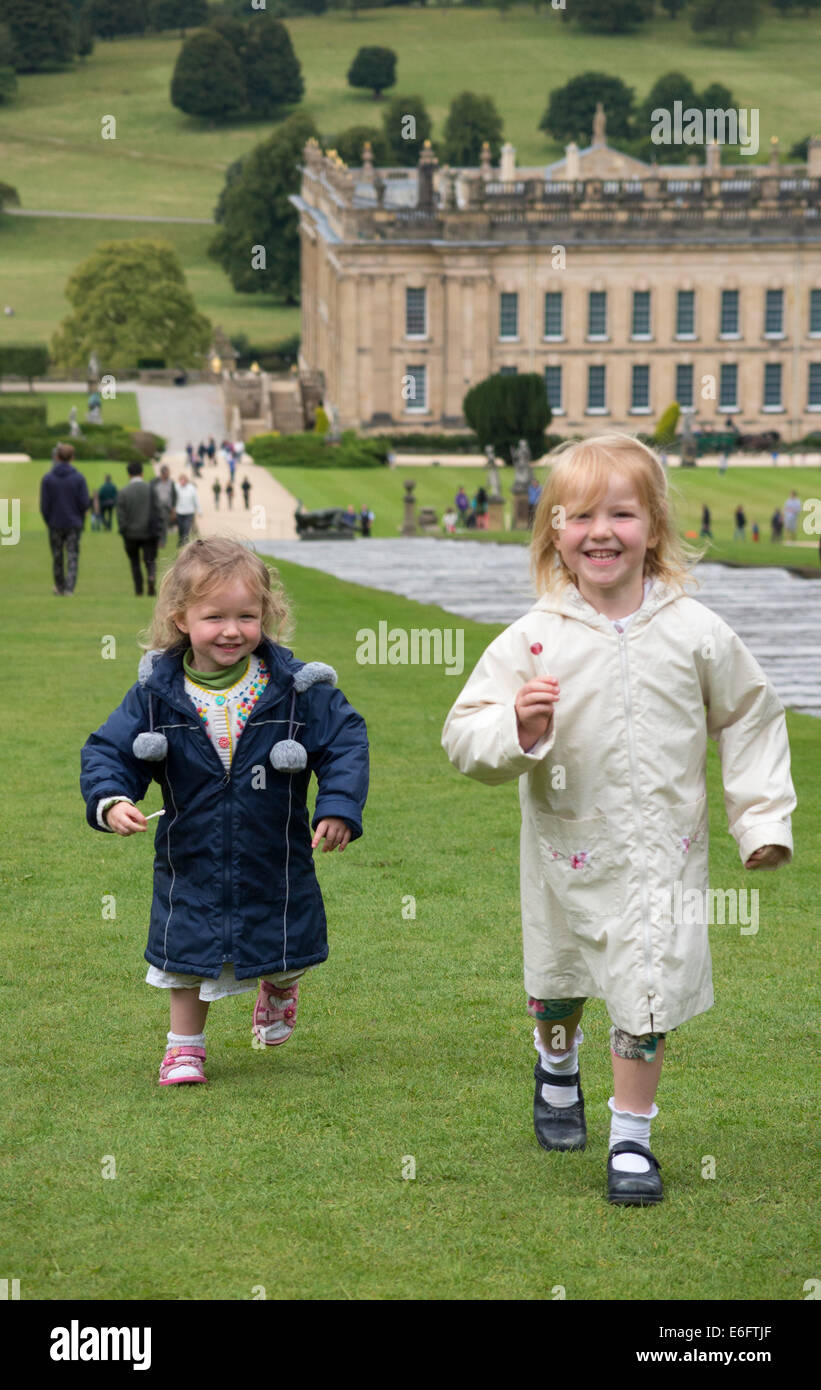 Junge Mädchen, Schwestern im Alter von drei und fünf Jahren laufen und spielen im Garten von Chatsworth House Nr Bakewell in Derbyshire. UK. Mädchen sind Model Released. Stockfoto