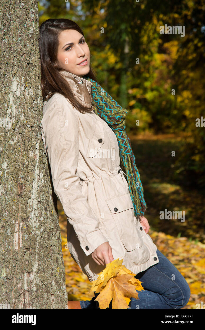 Träumen auf einem Baumstamm schlanke junge Frau im Herbst. Stockfoto