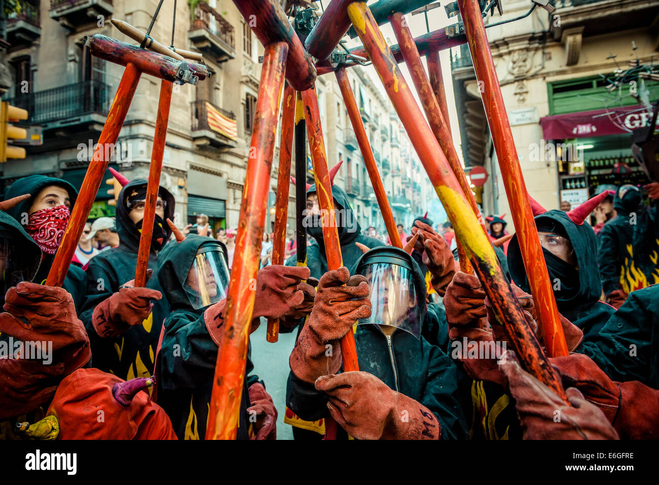 21. August 2014. Barcelona, Spanien: Kinder in Teufel Kostüme sammeln um ihre Feuerwerkskörper zu bekommen während die Kinder "Correfocs" bei der "Festa Major de Gracia" beleuchtet. Stockfoto