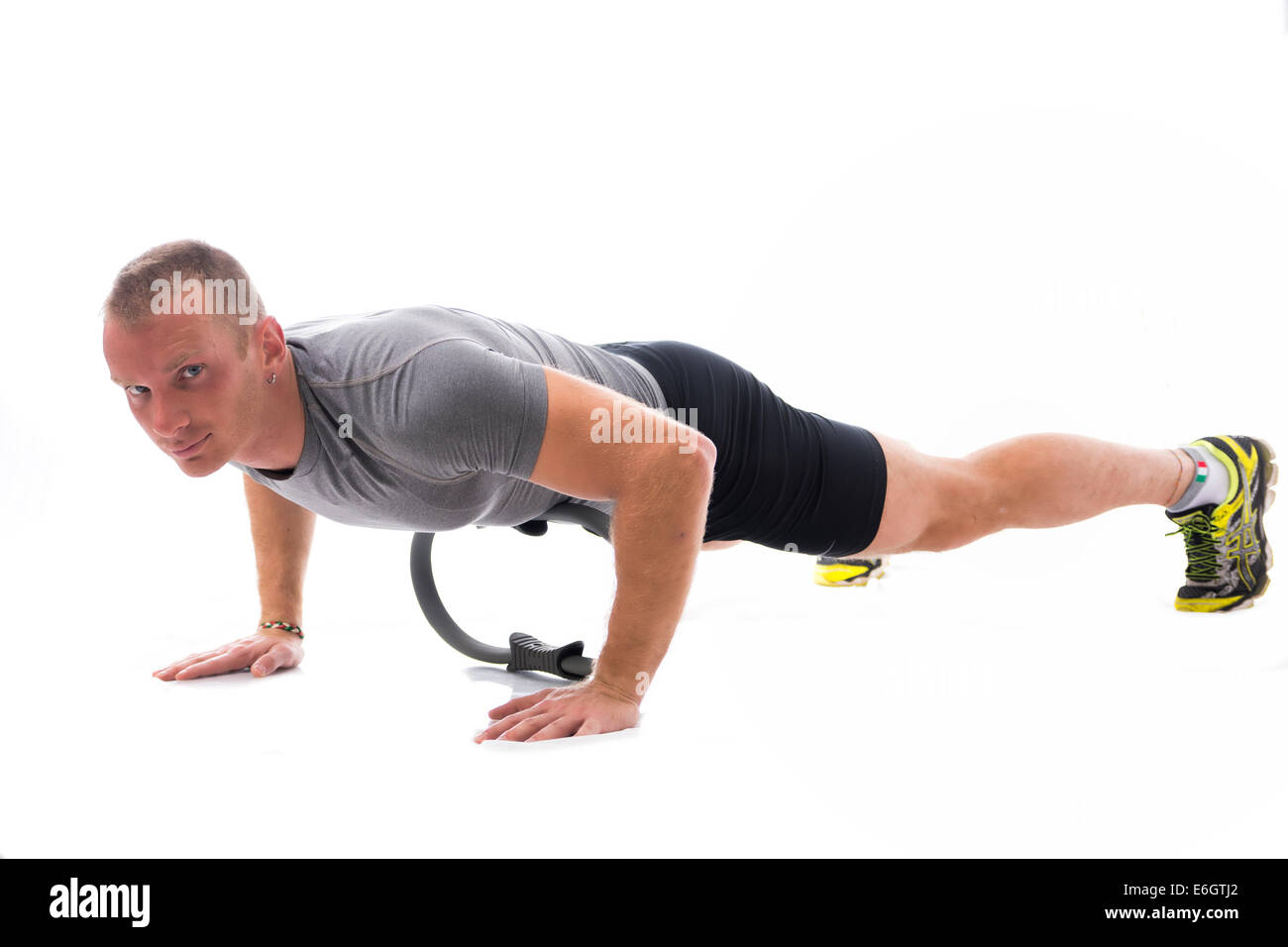 Junge blonde muskulöser Mann Training auf dem Boden mit Pilates Ring isoliert auf weiss Stockfoto