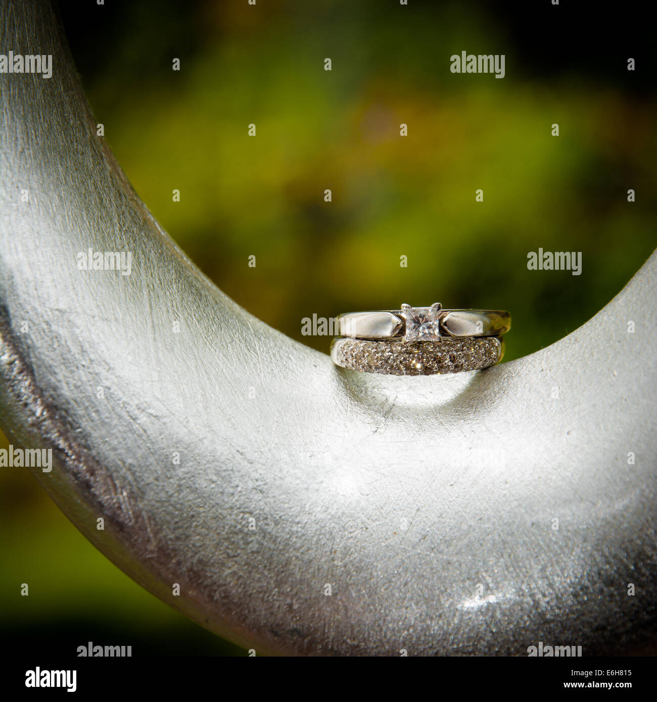 Ein Weißgold Diamant-Verlobungsring und Ehering werden auf einer modernen, Silber gebogene Objekt angezeigt. Stockfoto