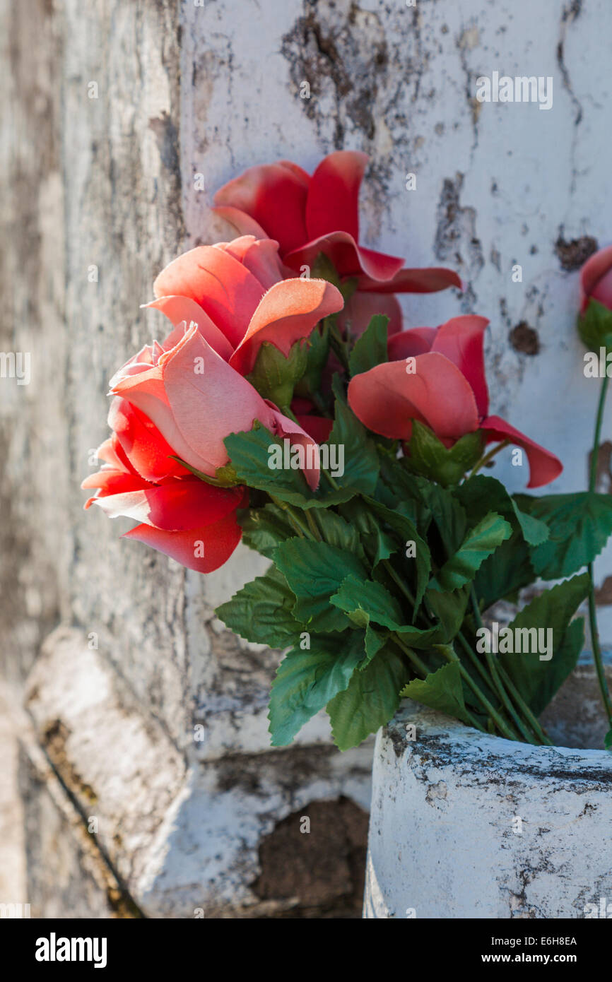 Rote Seide Rosen in Vase in einem oben genannten Boden-Grab in St. Louis Friedhof Nr. 1 in New Orleans, Louisiana Stockfoto