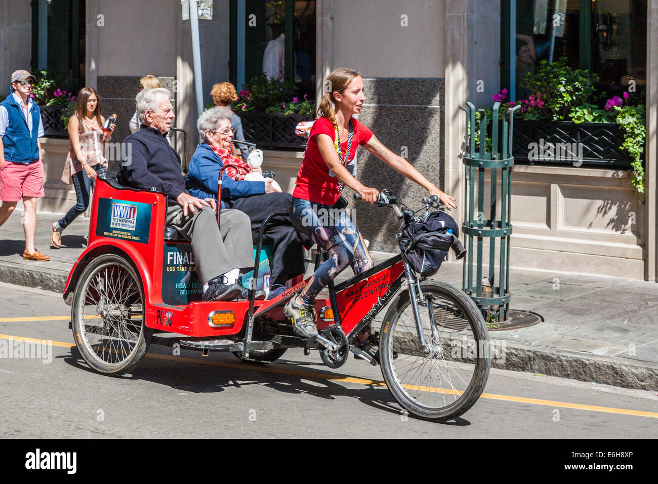 Weibliche Rikscha Fahrer tragen älteres Paar im French Quarter von New Orleans, Louisiana Stockfoto