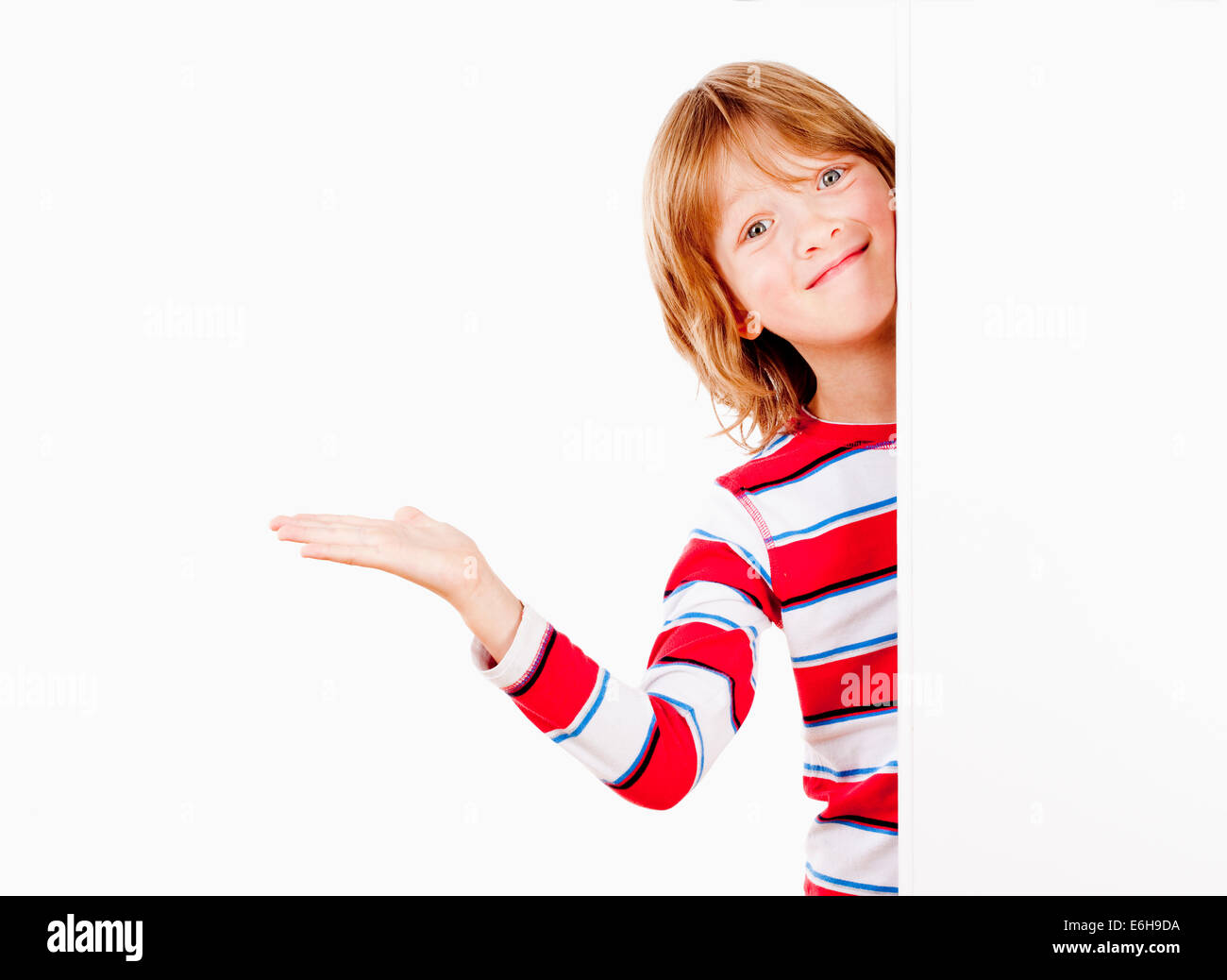 Junge Peeking Out hinter einer weißen Tafel mit seinem ausgestreckten Arm Stockfoto