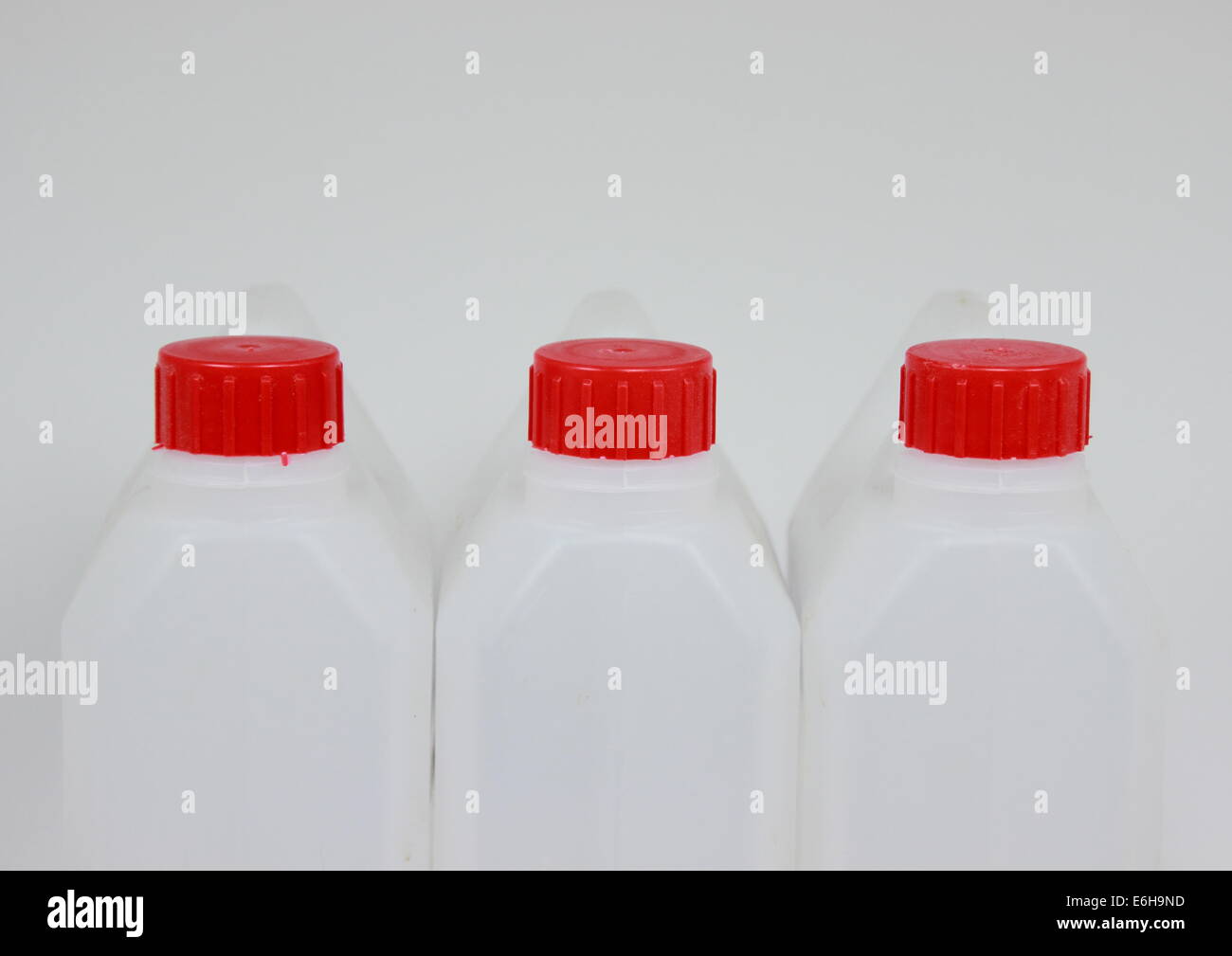 Drei leere Kanister aus weißem Kunststoff mit rotem Deckel Stockfoto