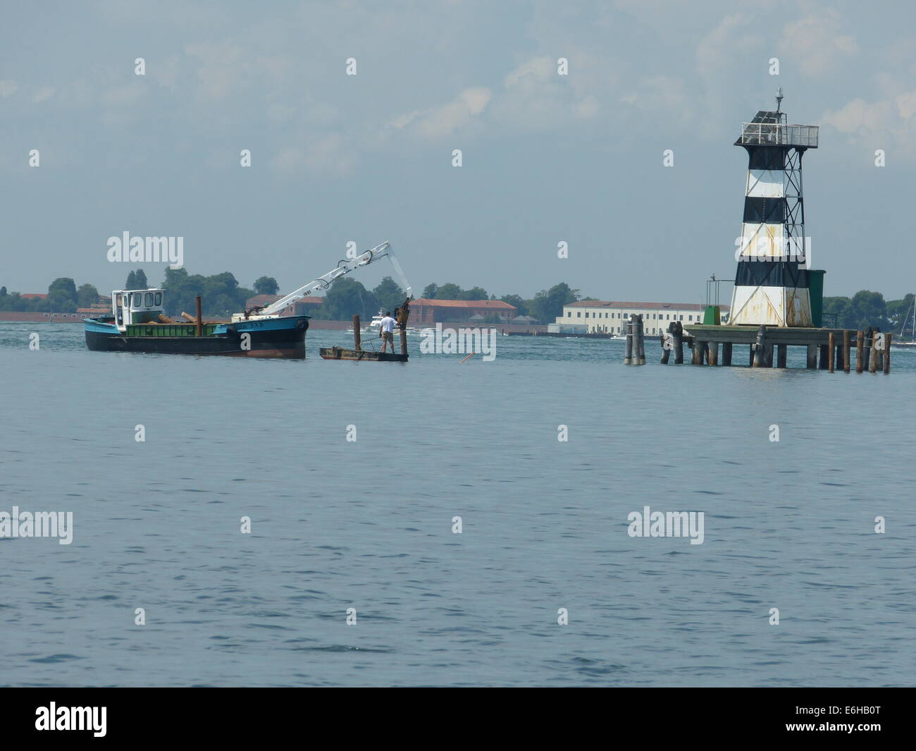 Arbeitsboot in der Lagune von Venedig und einen alten Leuchtturm Stockfoto
