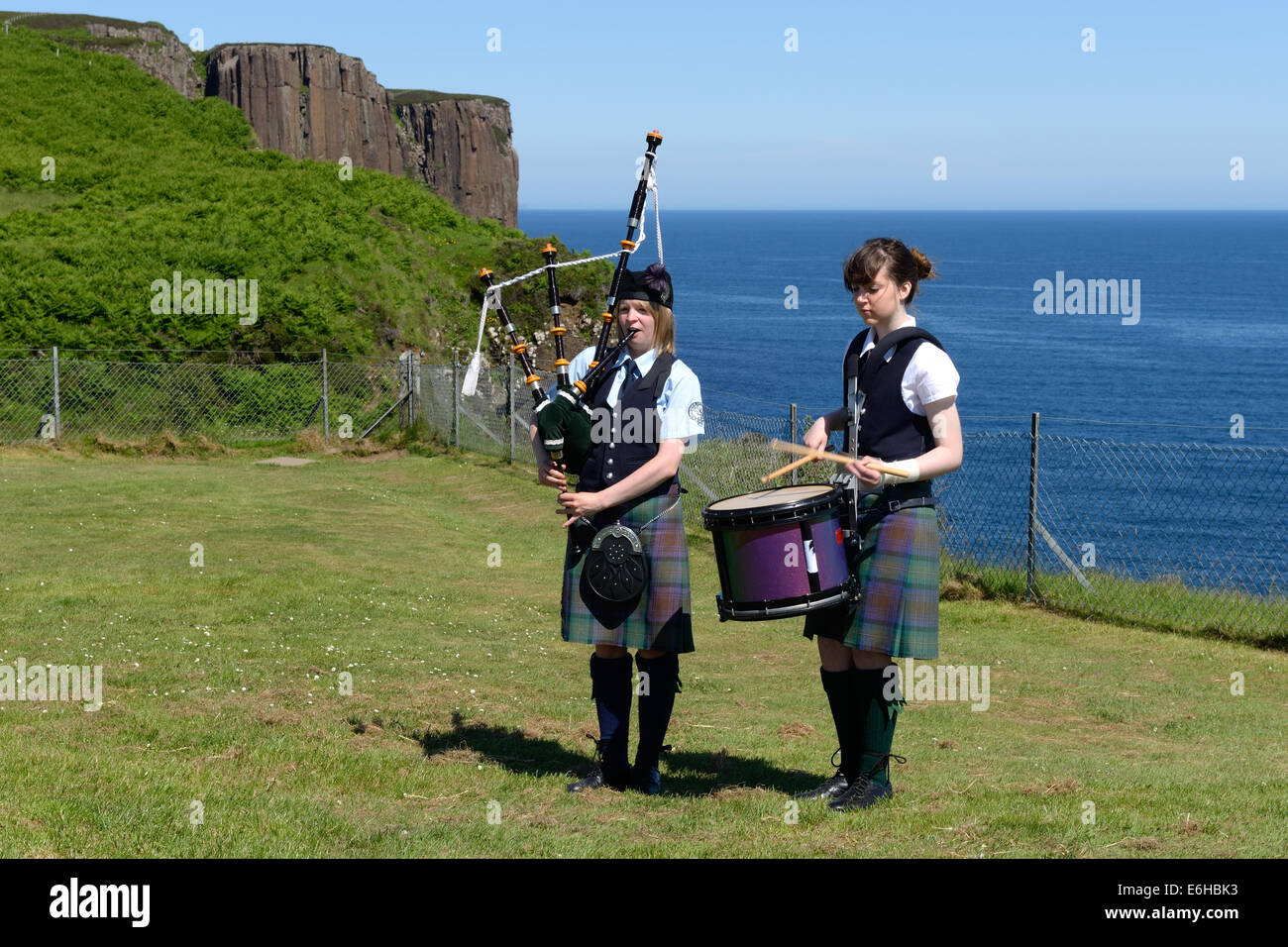 Zwei Mädchen im Teenageralter in Kilts unterhalten die Besucher am Kilt Rock Aussichtspunkt auf der Isle Of Skye Stockfoto