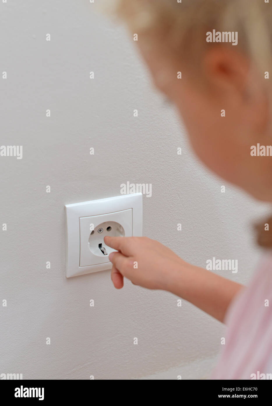 Kind steckt seine Finger in die Steckdose. Gefährliche Situation zu Hause. Stockfoto