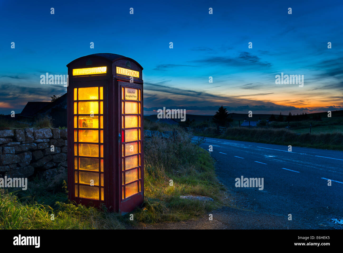 Alte rote Telefonzelle in der Abenddämmerung auf einer Landstraße in Dartmoor, Devon Stockfoto