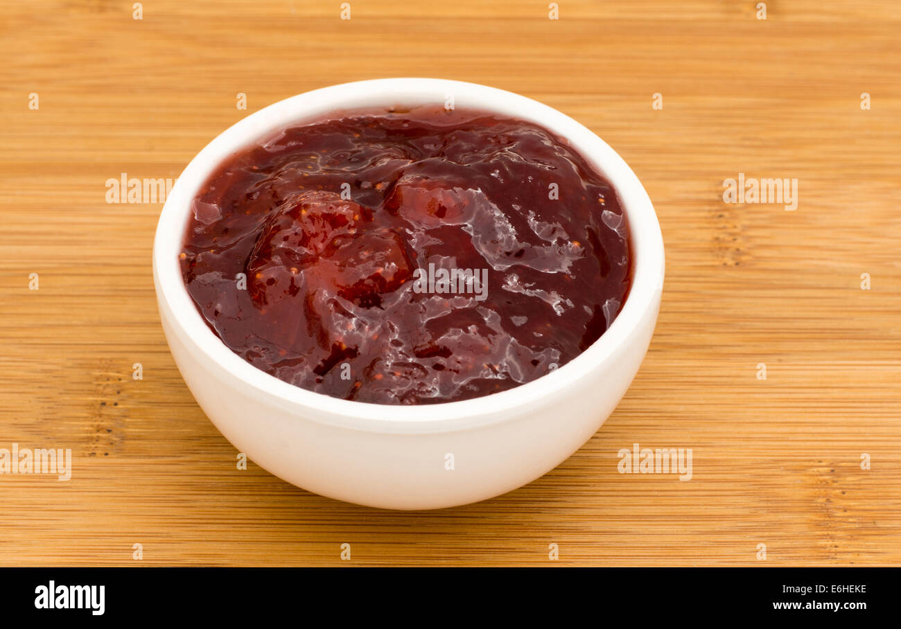 Kleinen Topf mit Erdbeer-Marmelade auf einem Holzbrett Stockfoto
