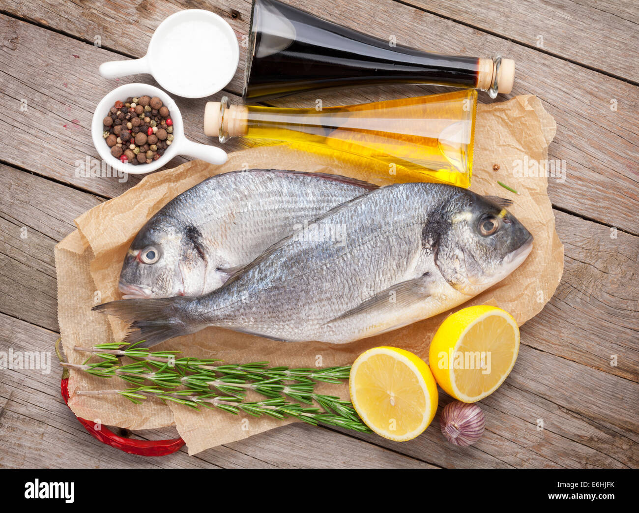 Dorado Frischfisch Kochen mit Gewürzen und Zutaten auf Holztisch Stockfoto