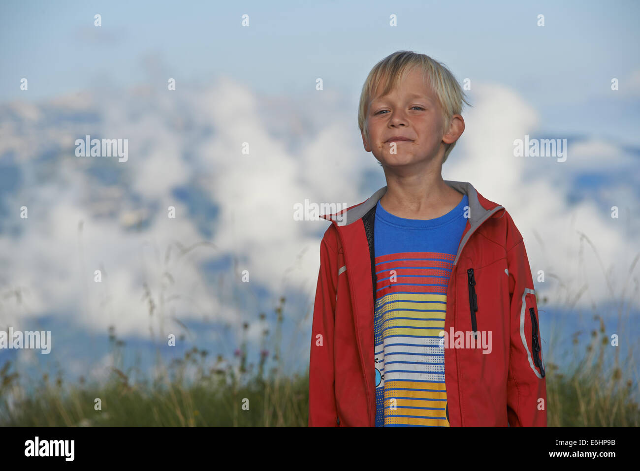 Porträt des Kindes Blond Boy lächelnd in Alpen Berg mit Wolken Hintergrund, Monte Altissimo, Italien, Porträt Stockfoto