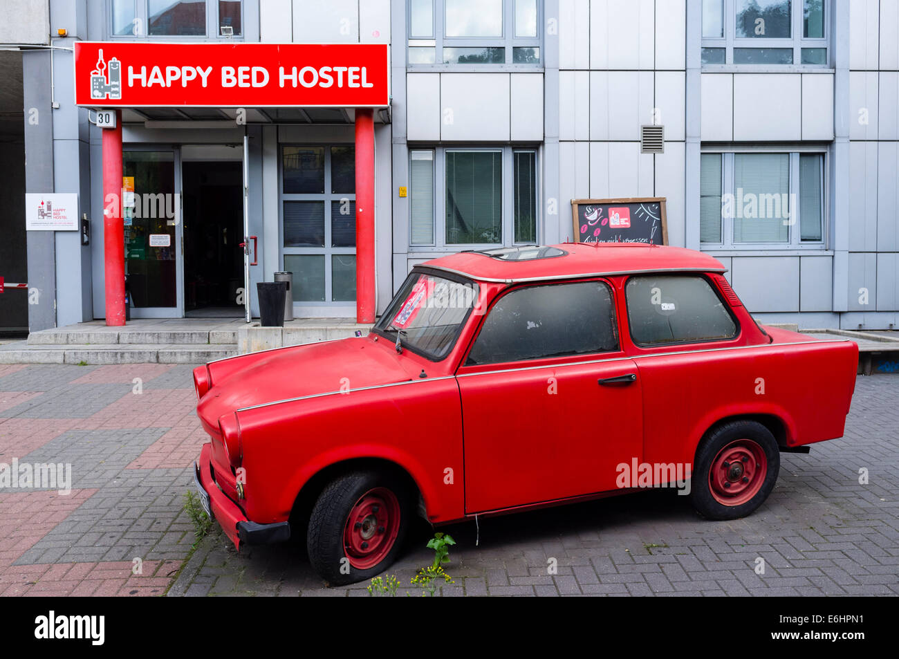 Außenseite des Happy Bett Budgethostel mit roten DDR Trabant Auto außerhalb in Berlin Deutschland Stockfoto