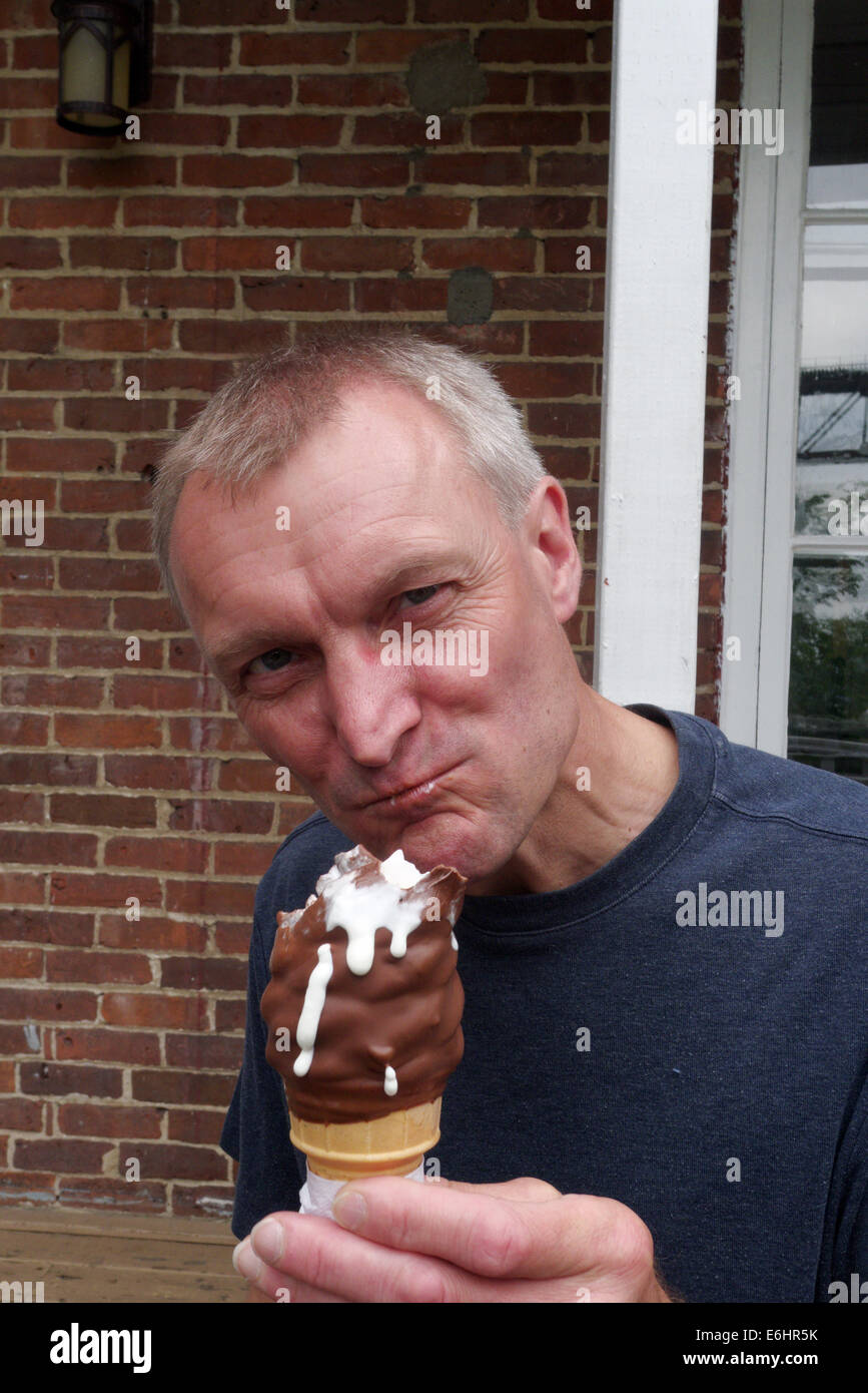 Ein Mann isst ein Eis mit einem feindlichen Ausdruck Stockfoto