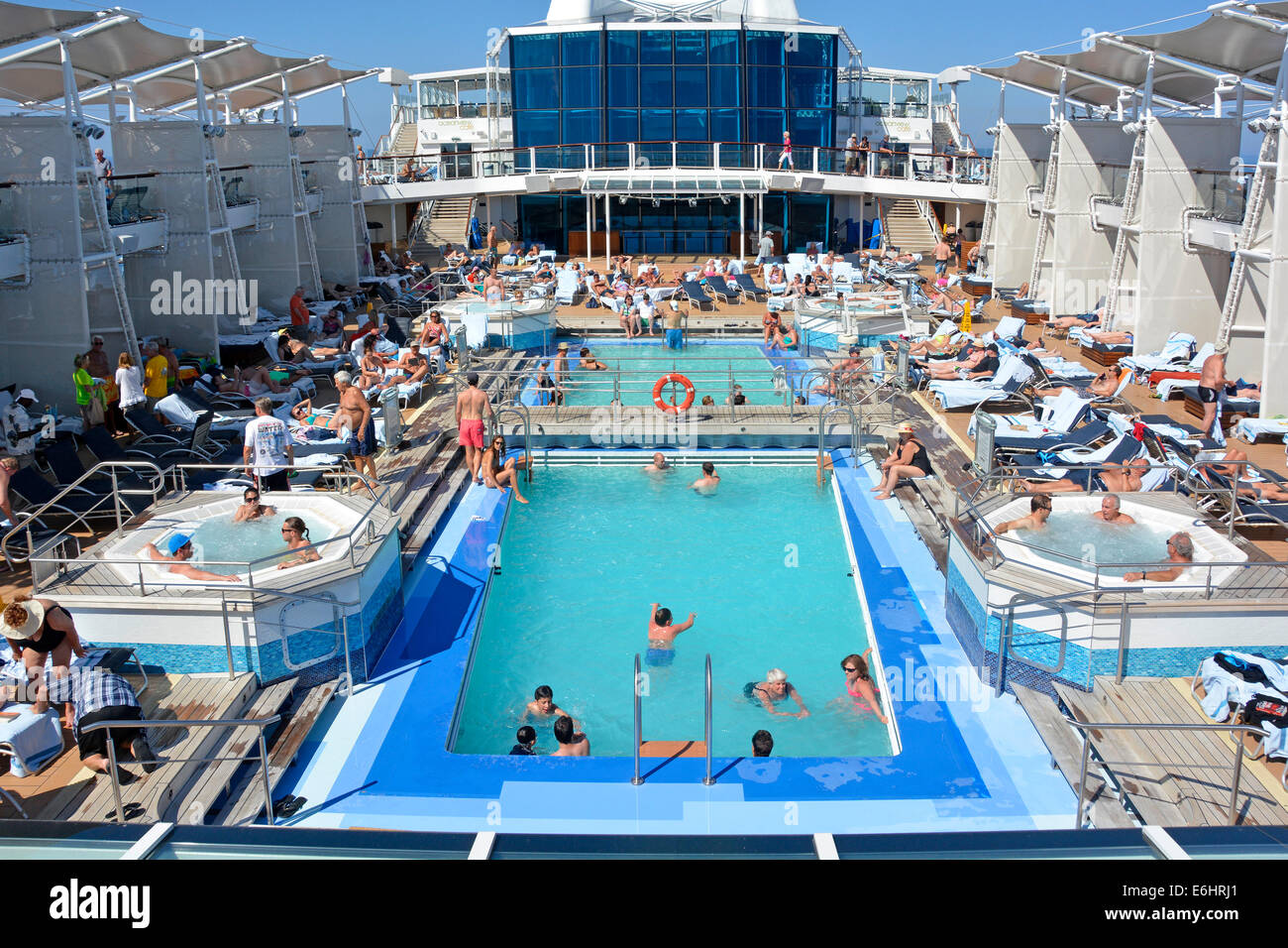 An Bord der Ruise-Schiff-Swimmingpools Jacuzzi-Einrichtungen, Leute entspannen sich auf überfüllten, beliebten Sonnenliegen, Sonnendeck, mediterrane Kreuzfahrt Stockfoto