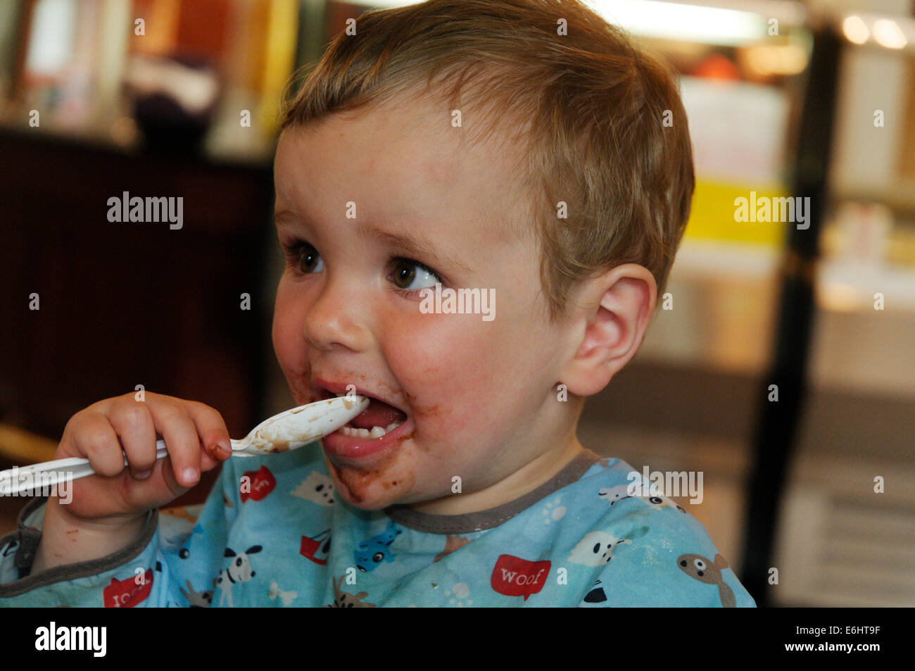 Ein zweijähriges Kind mit Schokoladensauce über das ganze Gesicht Stockfoto