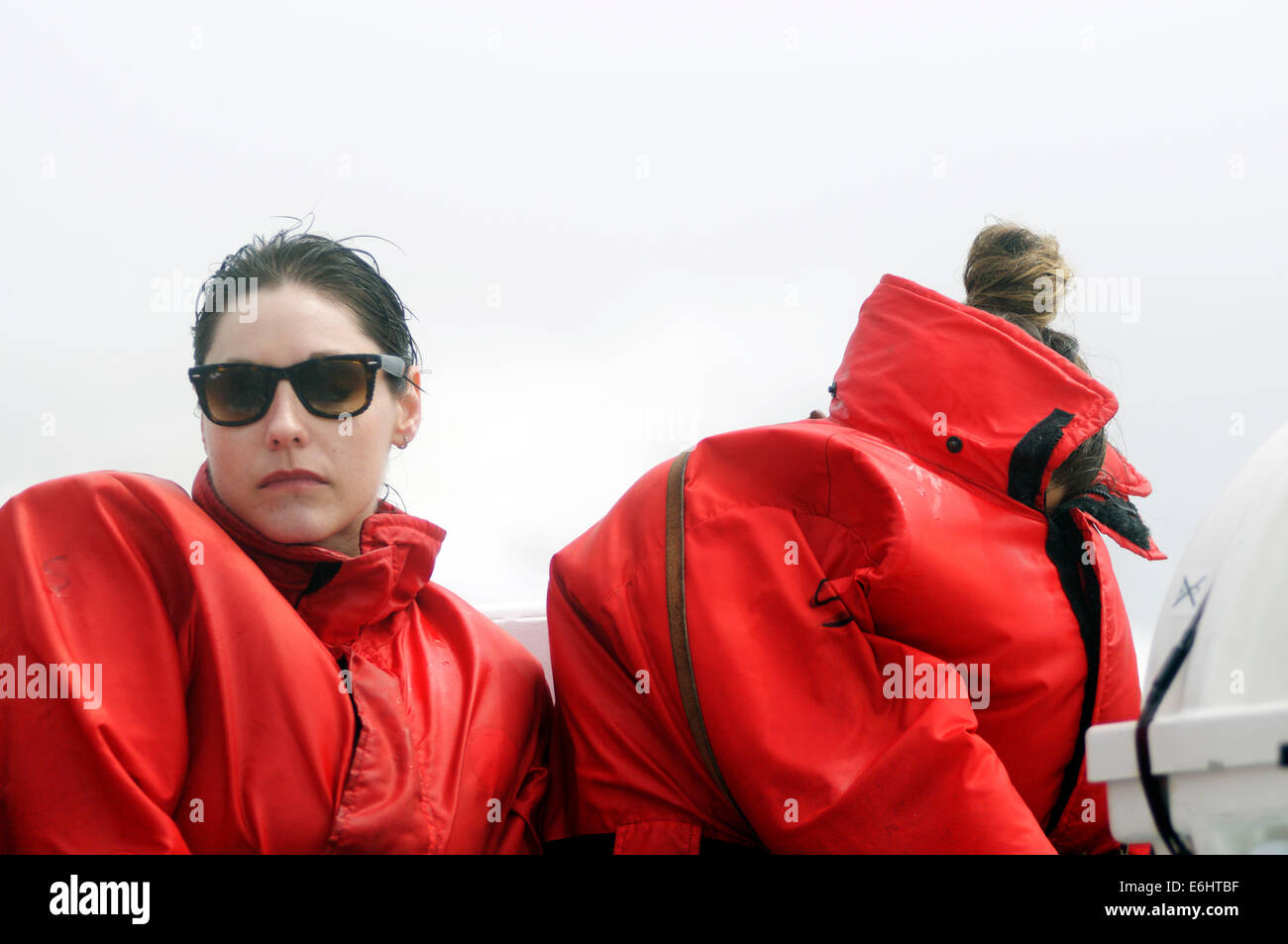 Zwei elende Frauen versucht sich zu verstecken vor der eisigen Kälte Spray auf ein Whale watching Boot fahren auf dem St. Lawrence Stockfoto