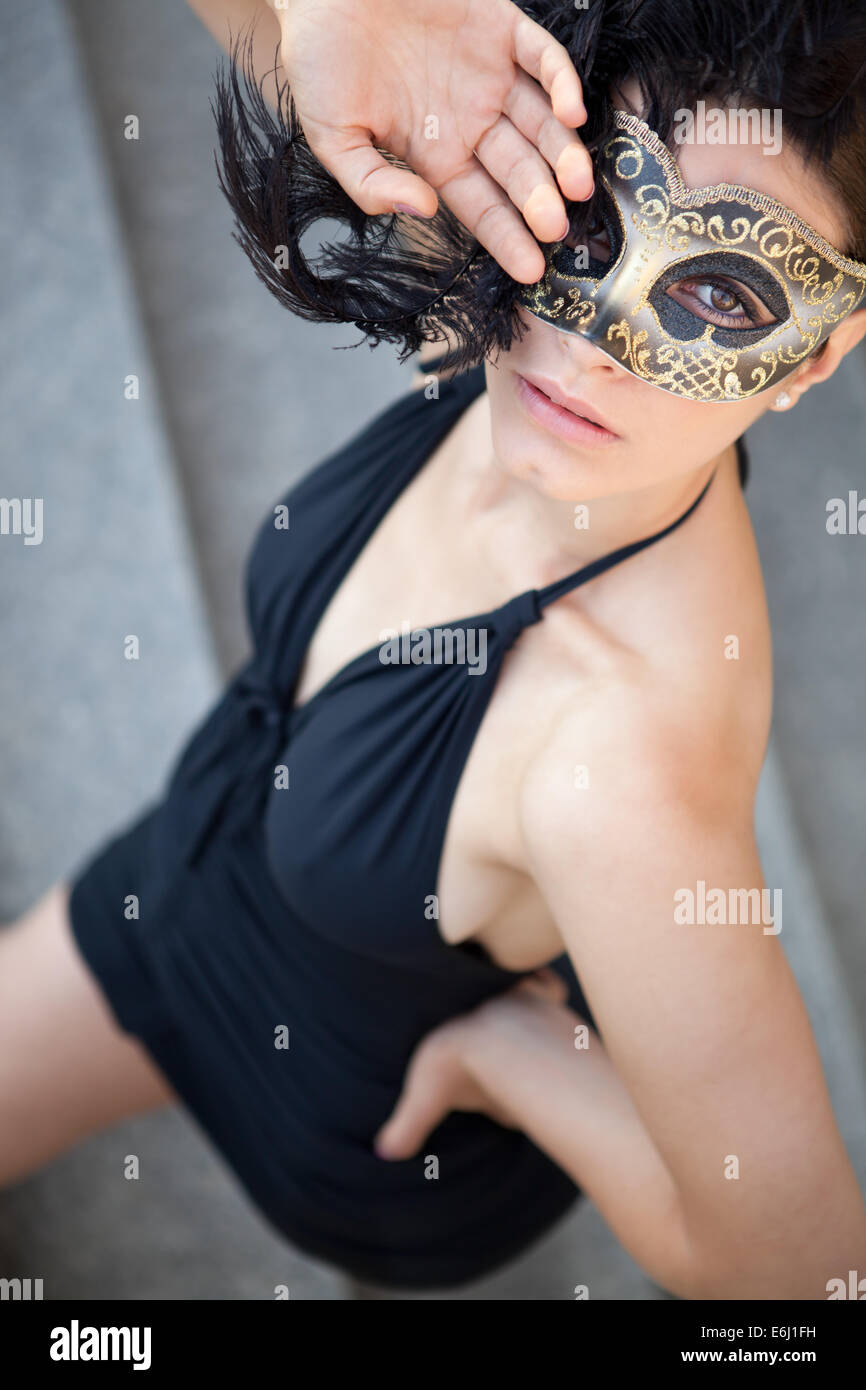 Sexy Mädchen in venezianische Maske mit schwarzen Federn und schwarzes Kleid. Stockfoto