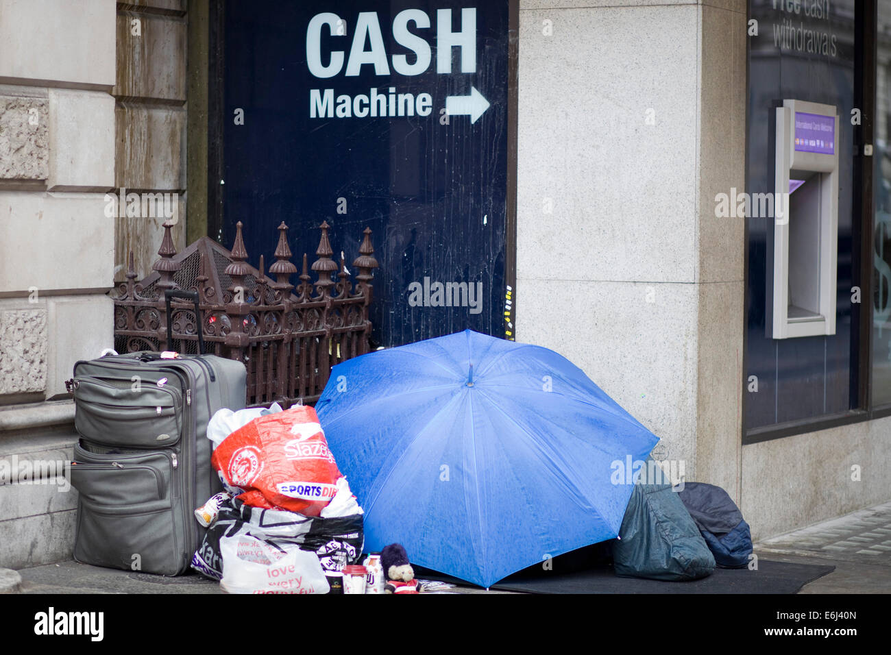 Obdachlose schlafen im Schaufenster mit Habseligkeiten neben ihnen im Regen London England Stockfoto