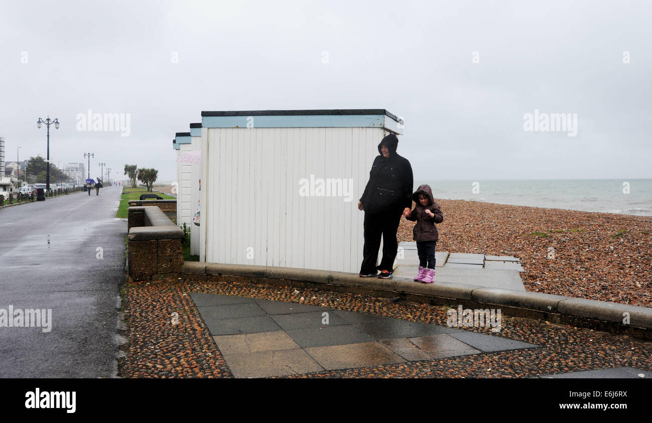 Worthing Sussex UK 25. August 2014 - ein paar versuchen und finden Unterkunft Worthing Strandpromenade entlang in das nasse Wetter heute nassen und windigen Wetter hat fegte über das Land auf diesem August Bank Holiday Montag Stockfoto