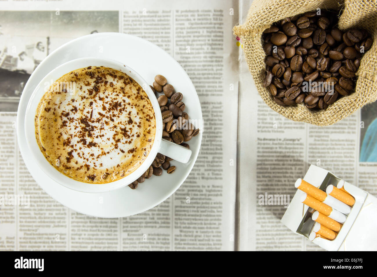Tasse Kaffee, gerösteten Bohnen und Packung Zigaretten angeordnet auf einer Zeitung Stockfoto
