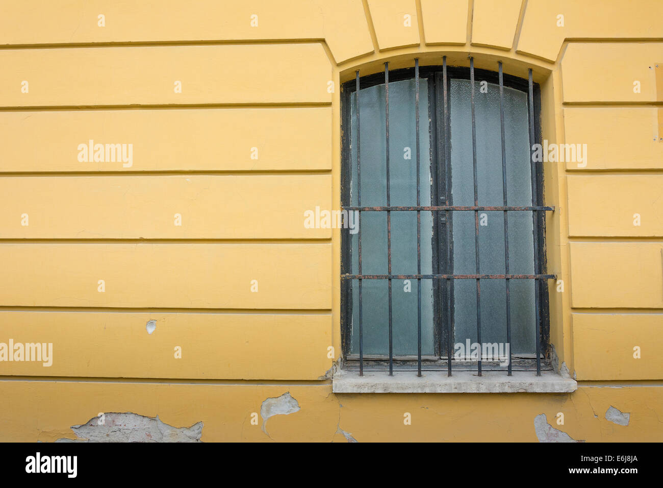 Schmiedeeisernen Fensterrahmen mit gelben Wand Stockfoto