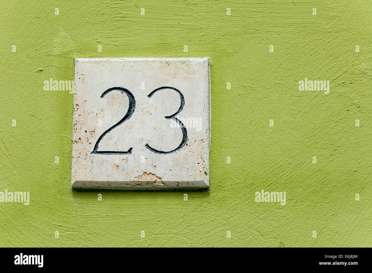 Hausnummer 23 auf eine Steinplatte mit einer grünen Wand-Hintergrund Stockfoto