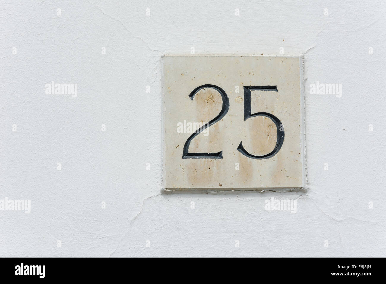 Hausnummer 25 auf eine Steinplatte mit einer grünen Wand-Hintergrund Stockfoto