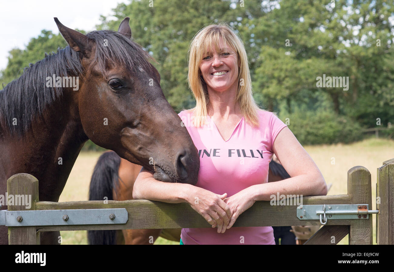 Stützte sich auf Tor tragen ein feines Stutfohlen-T-Shirt mit ihrem Pferd Frau Stockfoto