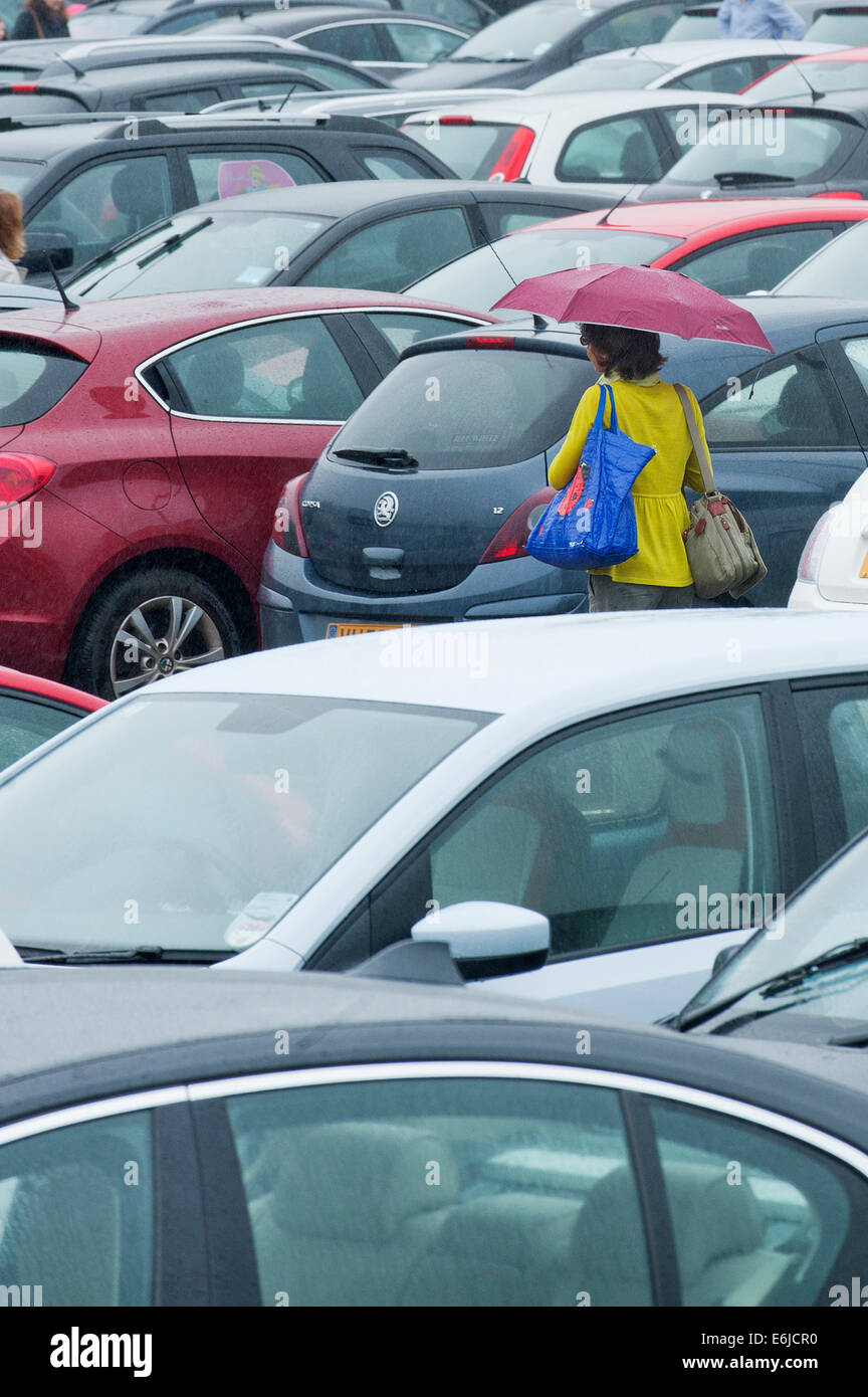 Swansea, Großbritannien. 25. August 2014. Wetter: Eine Frau geht durch eine gepackte Einzelhandel-Parkplatz - Menschen entscheiden, auf einem sehr nassen Bank Holiday Montag Einkaufen in Wales. Bildnachweis: Graham M. Lawrence/Alamy Live-Nachrichten. Stockfoto