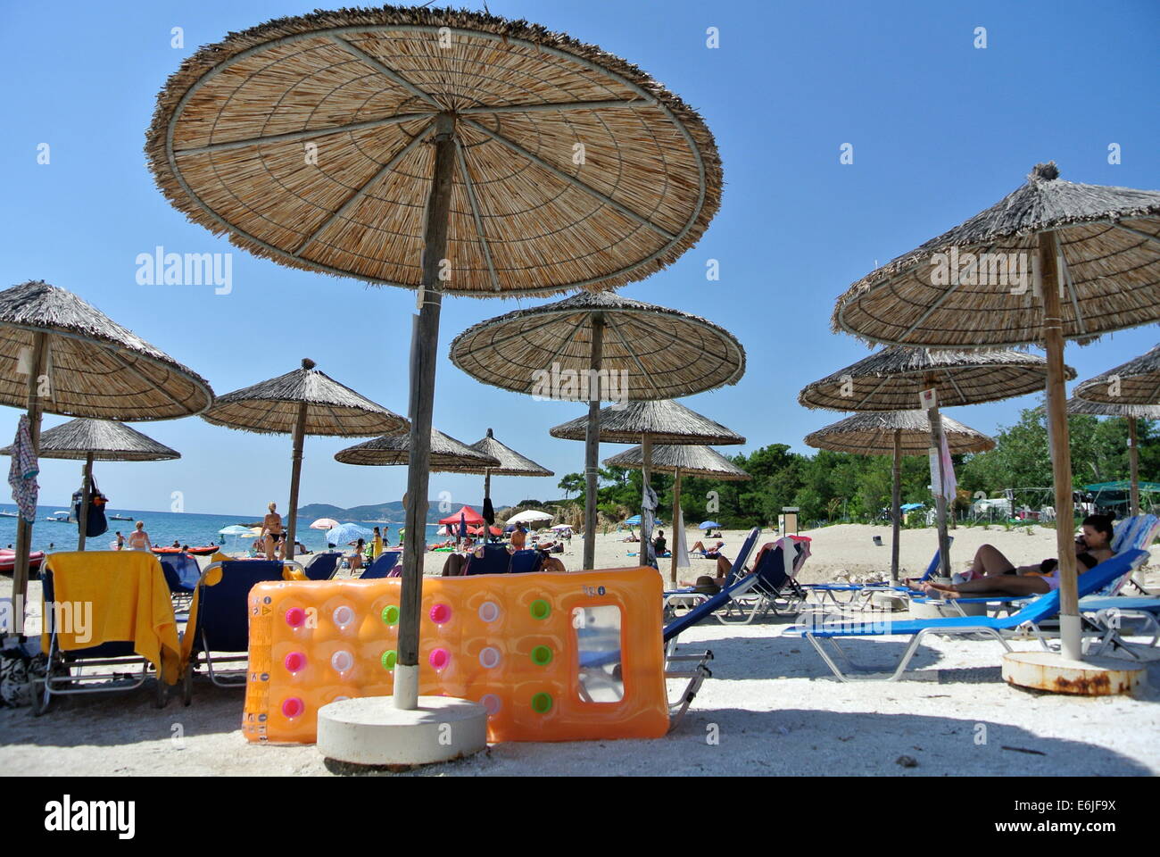 Sonnenschirme am sonnigen Strand mit Hüpfburg in Thassos, Griechenland Stockfoto