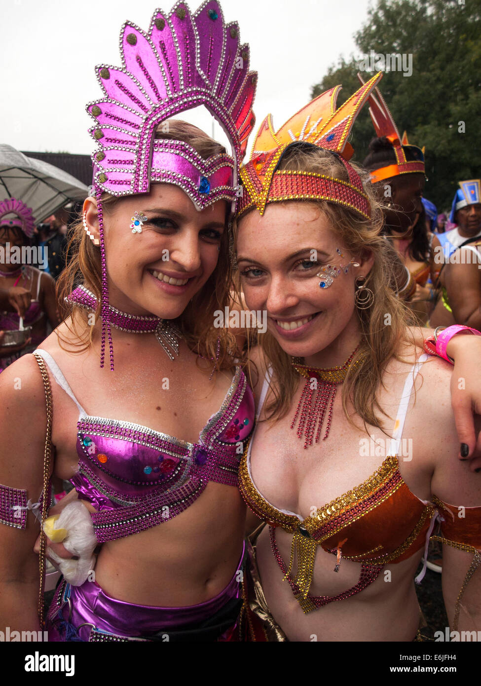 London, UK. 25. August 2014. Zwei Frauen in rosa und orange Kostüme lächelnd im Regen an der Notting Hill Carnival London, UK. Bildnachweis: Mamusu Kallon/Alamy Live-Nachrichten Stockfoto