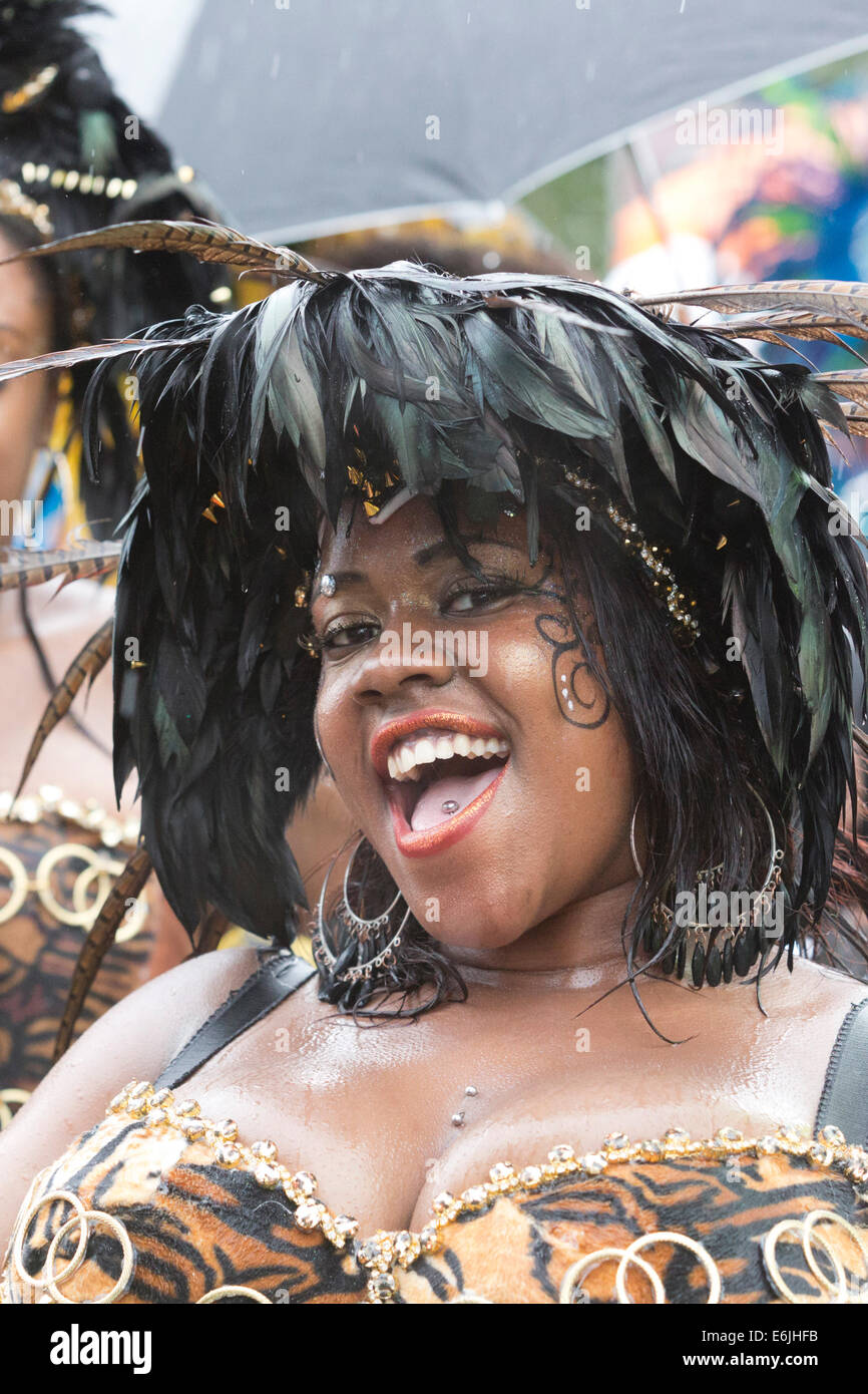 London, UK. 25. August 2014. Besucher und Teilnehmer der Notting Hill Carnival 2014 Bank Holiday Montag Parade nass auf ihrer Haut bekam, aber das Wetter konnte nicht die Nachtschwärmer-Geist - dämpfen, obwohl viele Zuschauer ausblieb. Foto: Nick Savage/Alamy Live-Nachrichten Stockfoto