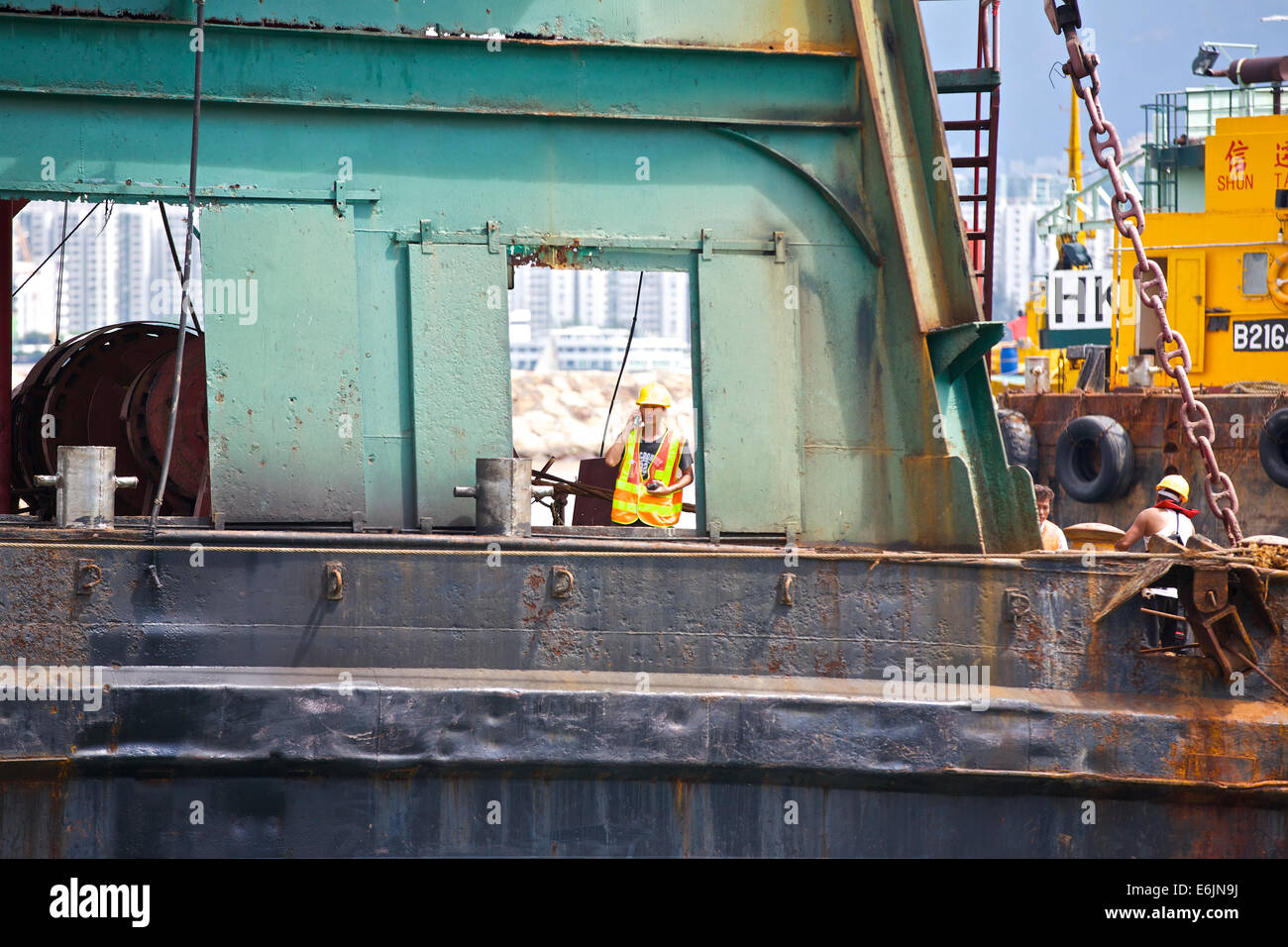 Gespräche für den Job. Ingenieur Gespräche auf seinem Handy auf einem Derrick Barge In der Causeway Bay Typhoon Shelter, Hong Kong. Stockfoto