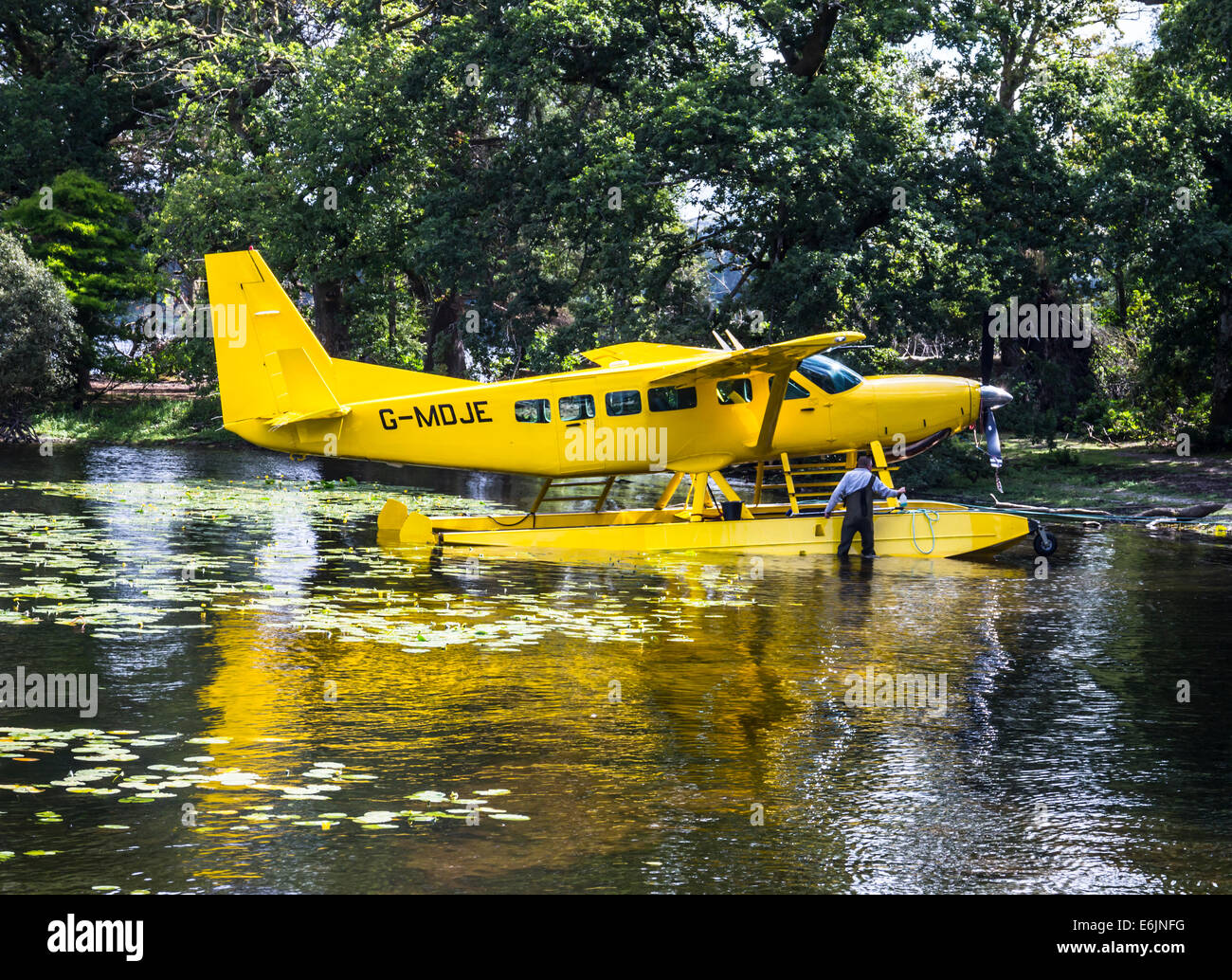 Mann Reinigung eine gelbe Cessna C208 Caravan Amphibian Wasserflugzeug, Loch Lomond, Schottland. Stockfoto