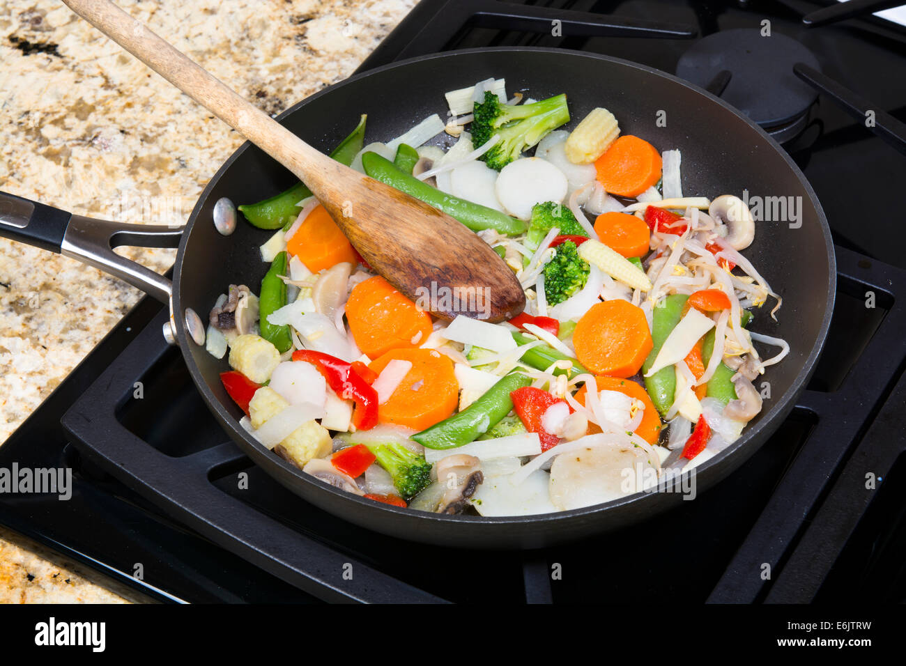 Frische gemischte Gemüse unter Rühren braten mit Zwiebeln, Karotten, Erbsen, Paprika und Sprossen in einer Pfanne Herd simmering. Stockfoto
