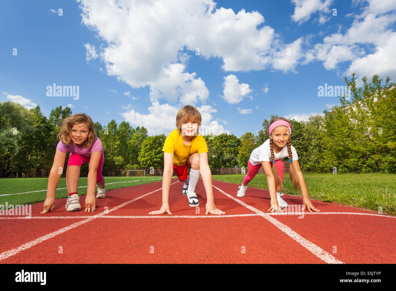 Lächelnde Kinder auf Biegen Knie startbereit Stockfoto