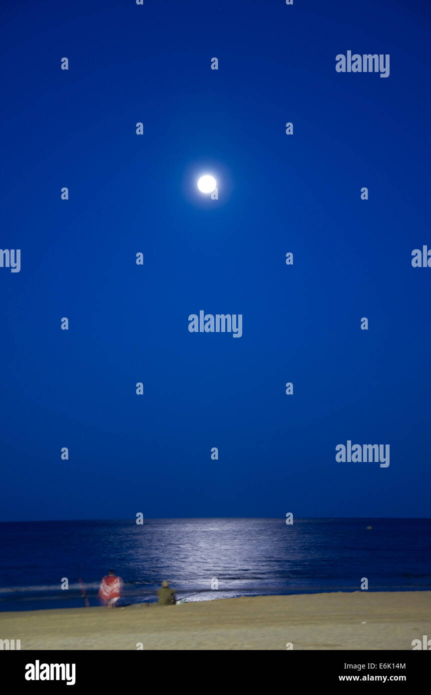 Eine Nachtaufnahme von verschwommen zu zweit am Strand vom Mond beleuchtet Stockfoto