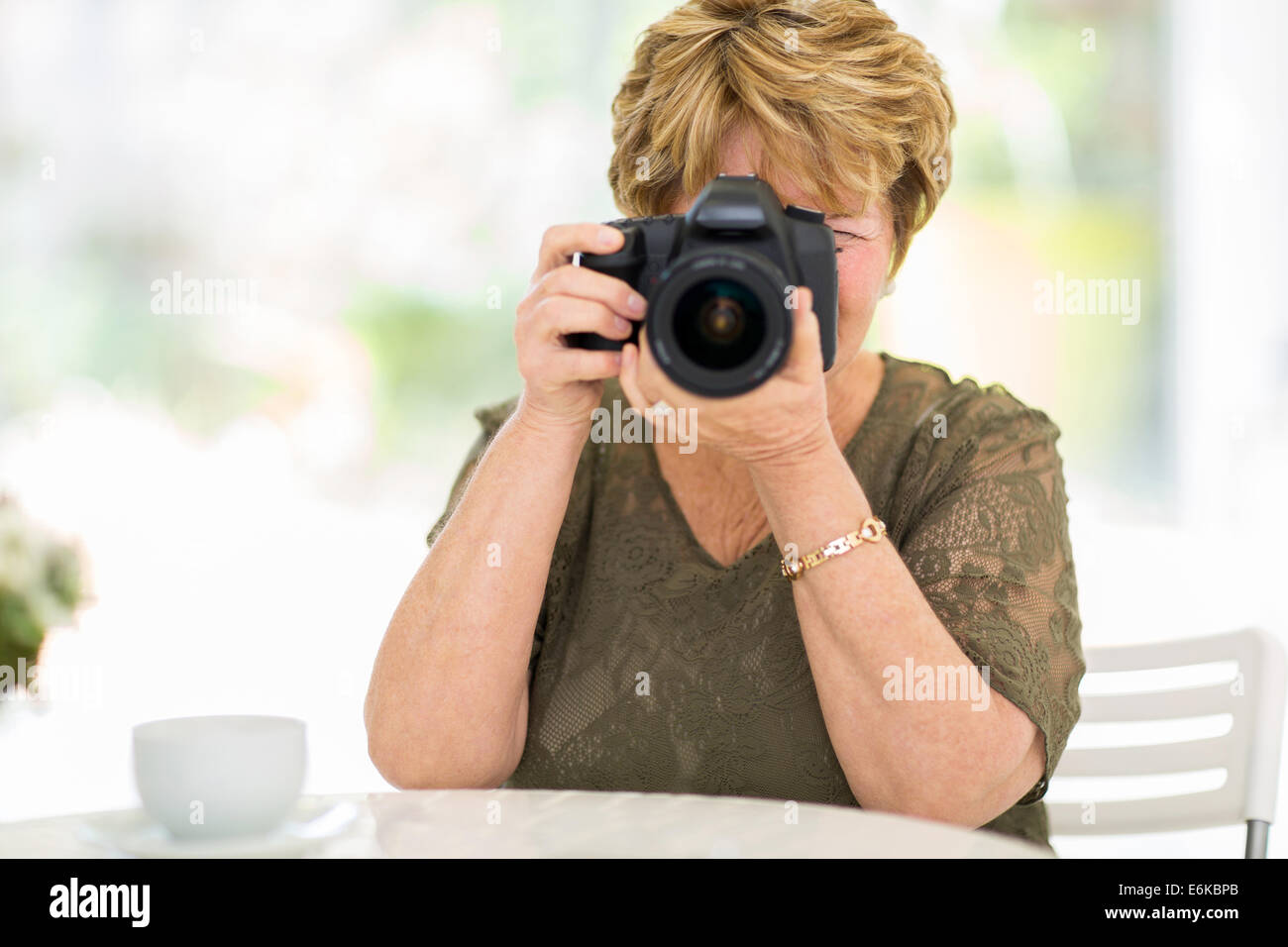 ältere Frau fotografieren mit digitalen SLR-Kamera zu Hause Stockfoto