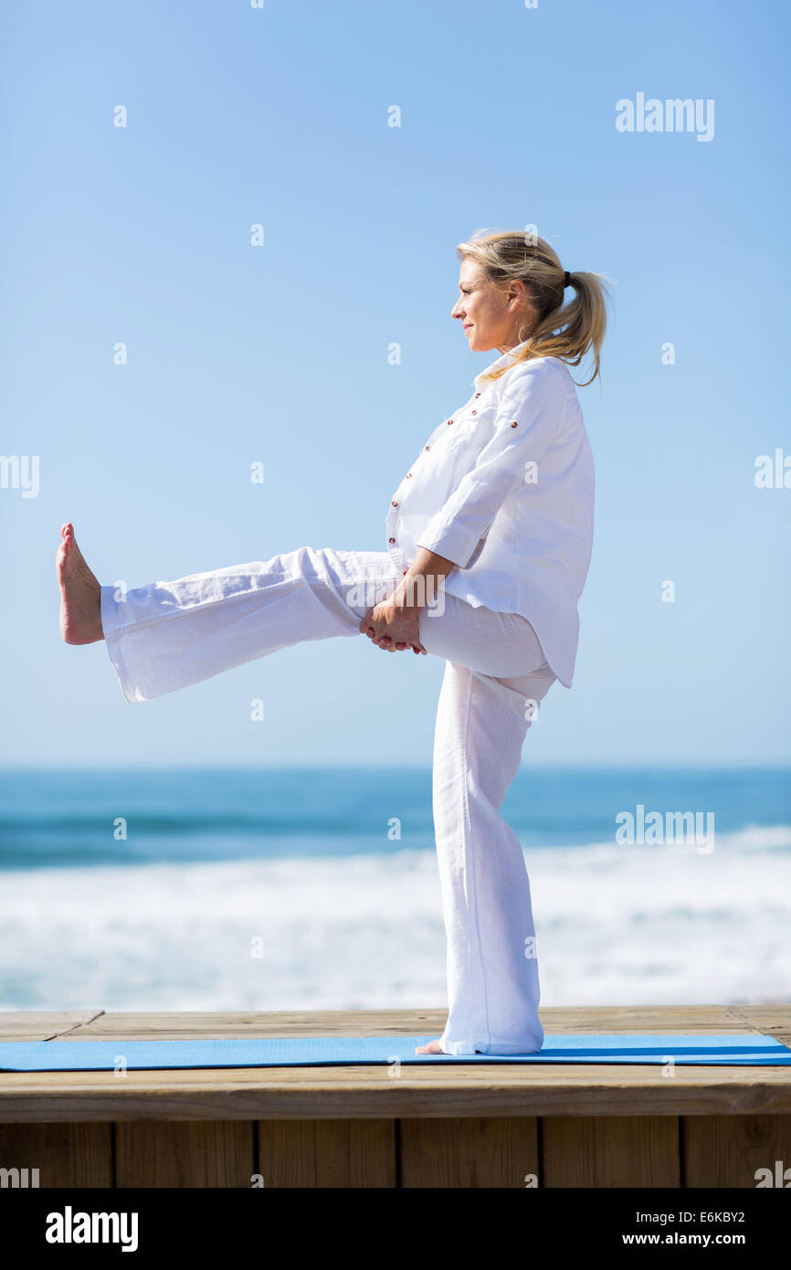 Seitenansicht des Fit senior Frau Strecken am Strand Stockfoto