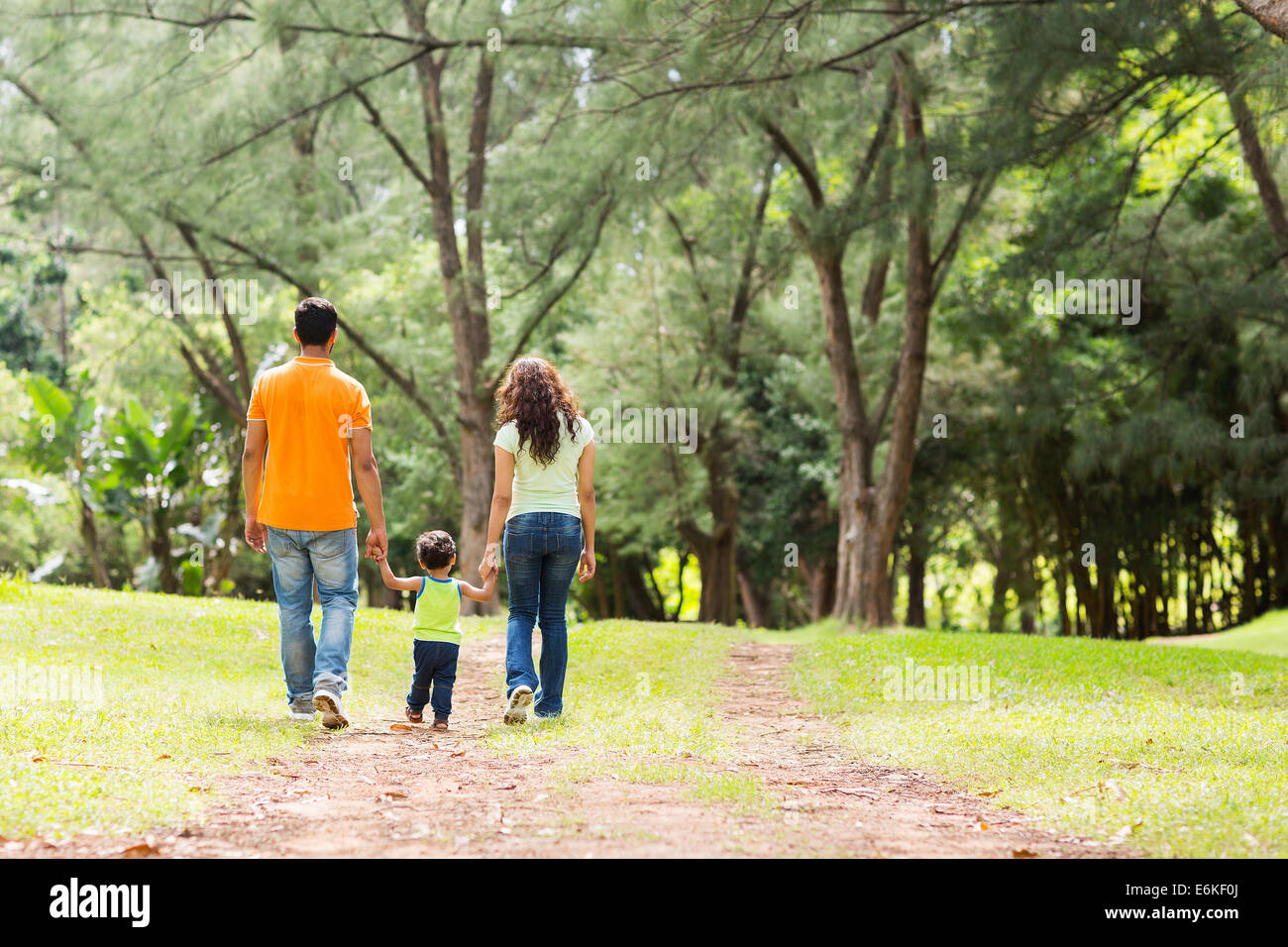 Rückansicht der jungen Familie Hand in Hand spazieren im Wald Stockfoto