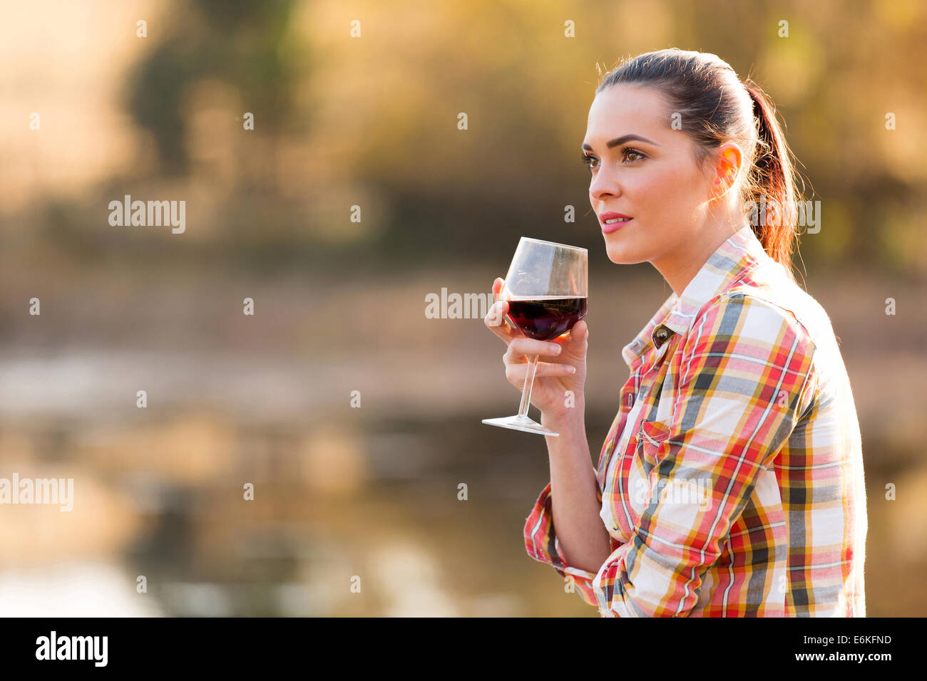 nachdenkliche junge Frau hält Glas Wein im Freien im Herbst Stockfoto