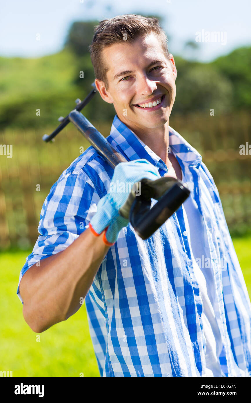 gut aussehender junger Mann hält eine Garten Gabel Stockfoto