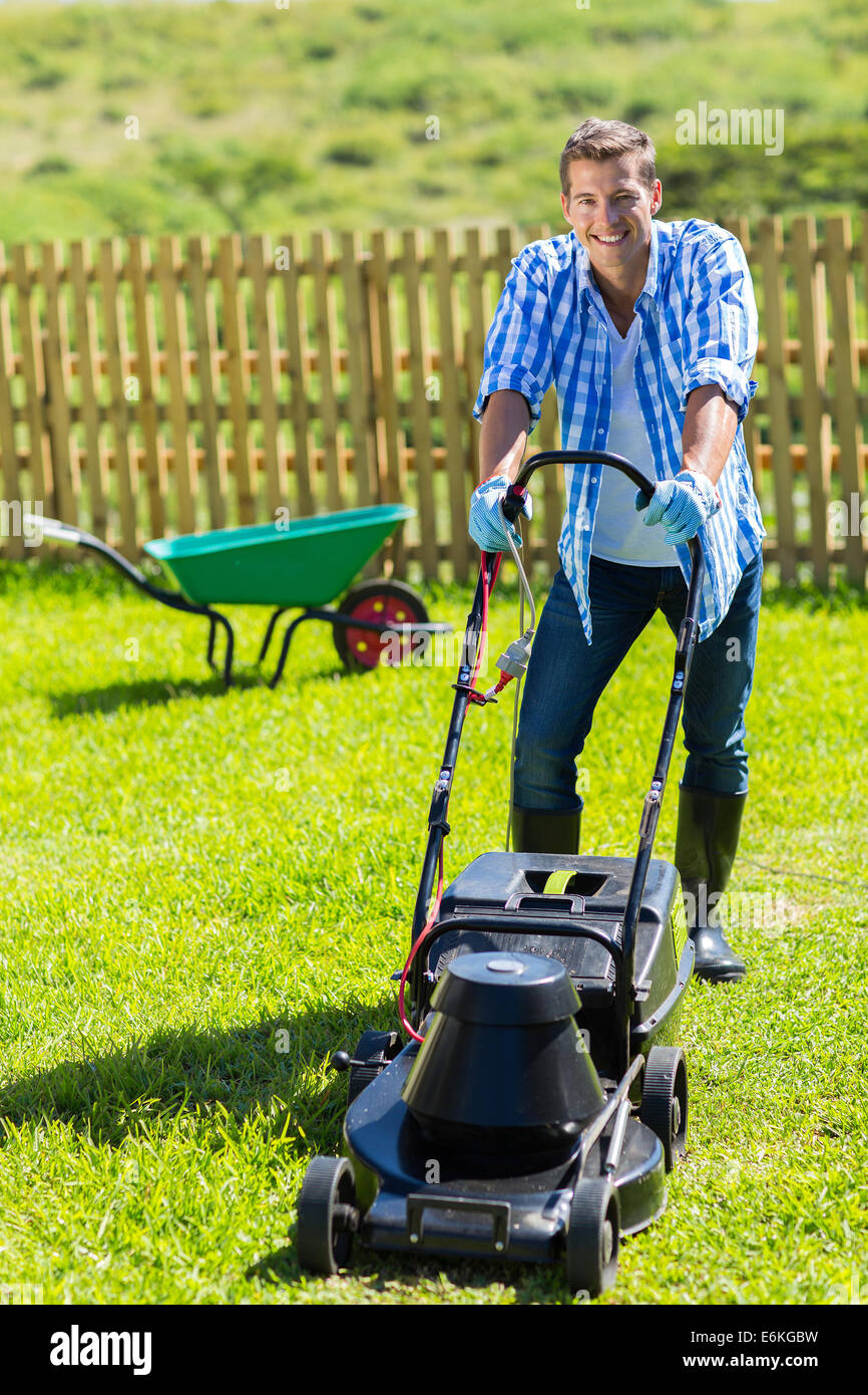 fröhlicher Mensch Rasenmähen in seinem Haus Garten Stockfoto