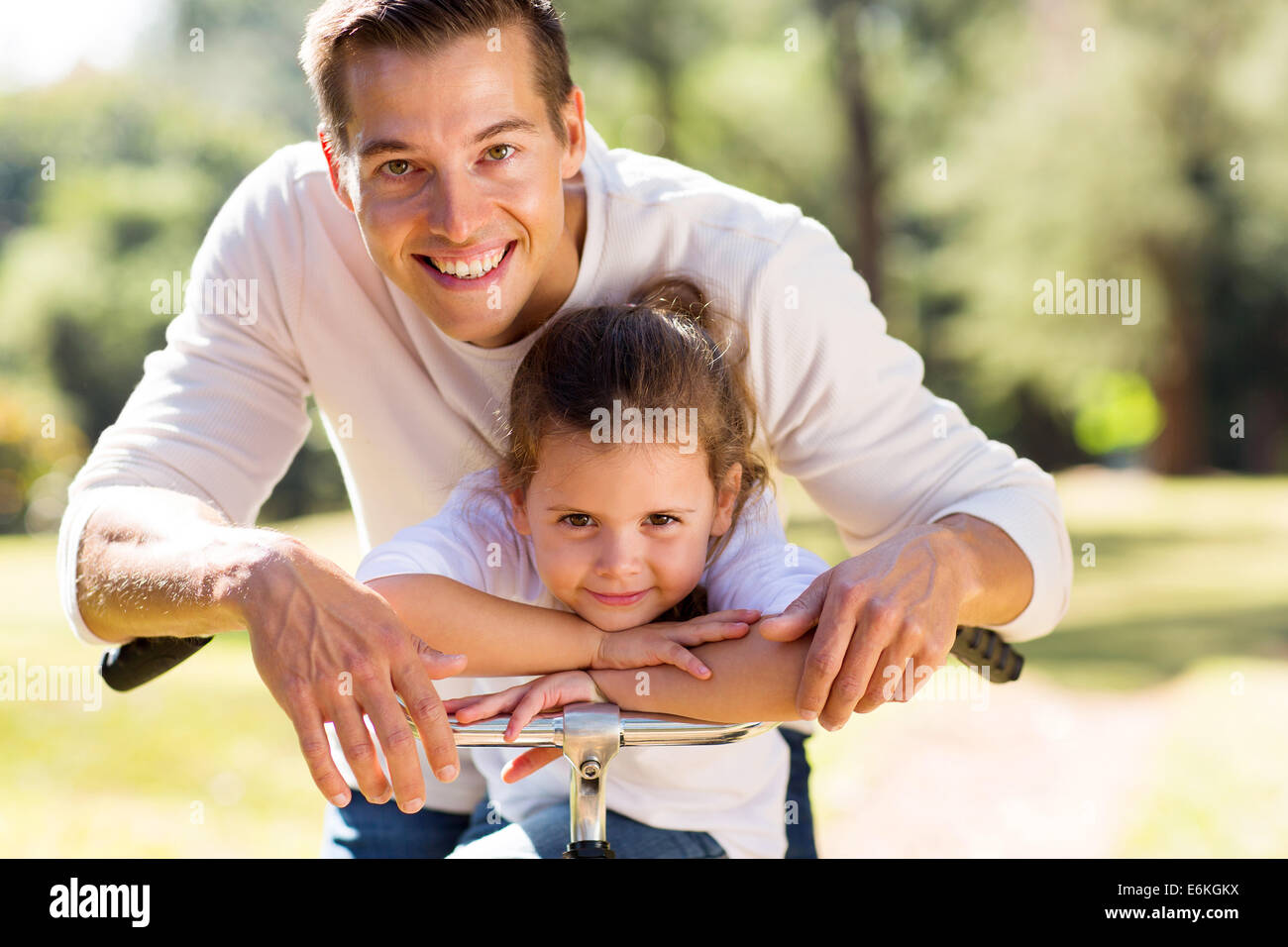 Porträt der glückliche Vater und seine süße Tochter draußen im Wald auf einem Fahrrad Stockfoto
