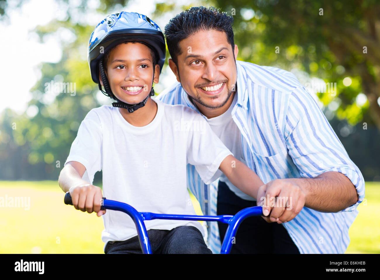 fröhliche indischer Mann helfen, sein Sohn, mit dem Fahrrad im Wald Stockfoto