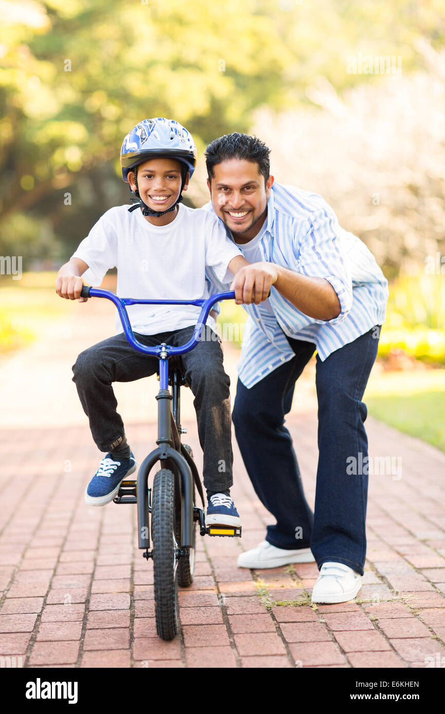 glückliche kleine Indianerjunge lernen, mit dem Fahrrad mit Hilfe seines Vaters Stockfoto