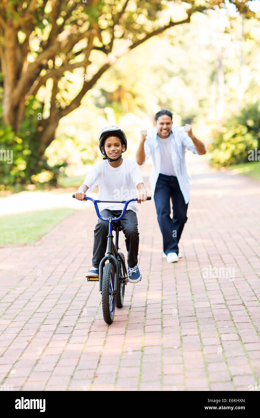 glücklicher Vater jubeln, wenn sein Sohn auf seine eigenen zum ersten Mal ein Fahrrad fahren können Stockfoto