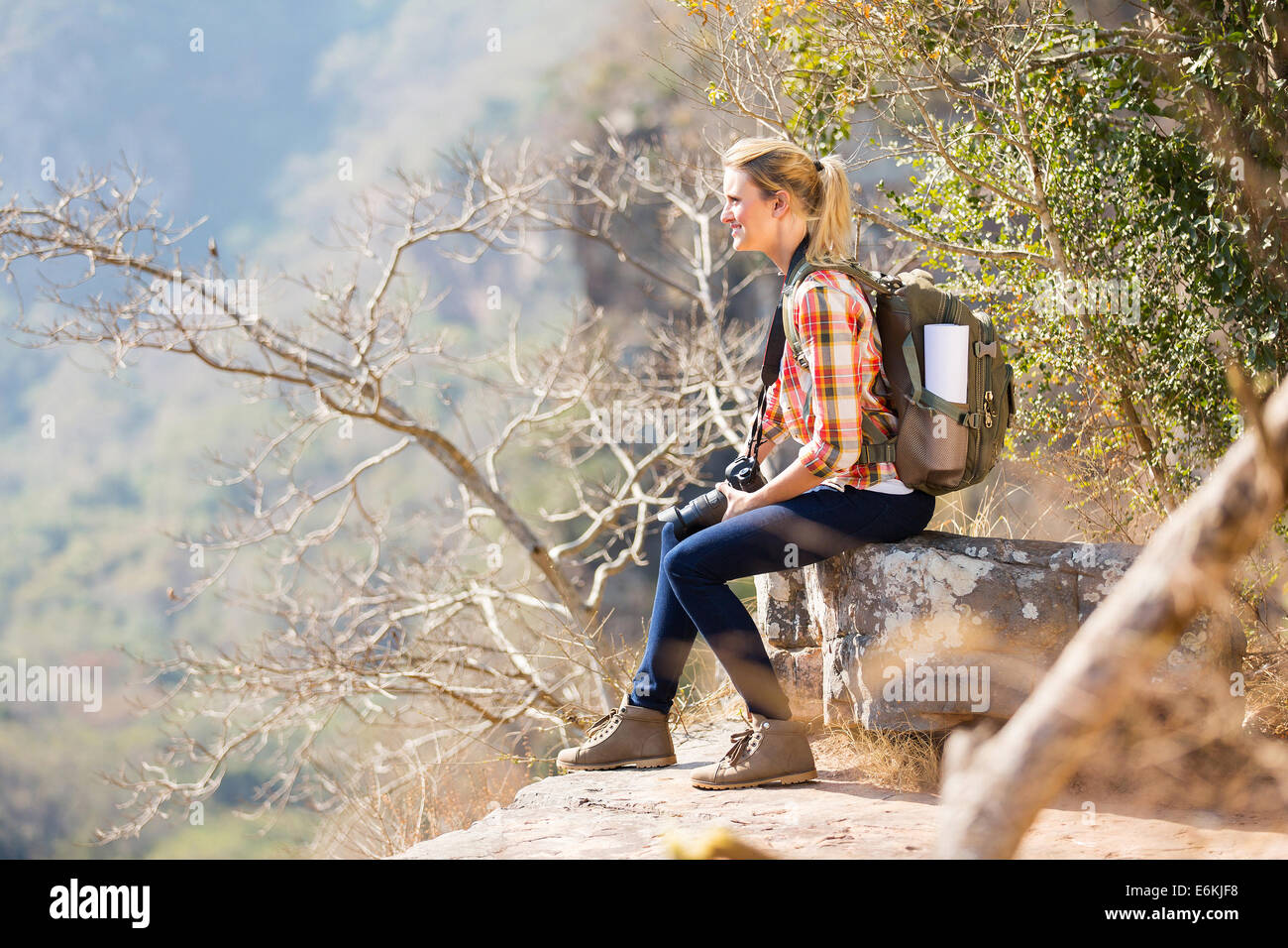 junge Frau sitzt auf dem Rand der Klippe in den Bergen Stockfoto